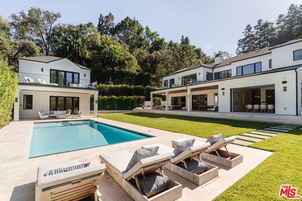 Poised behind gates on an expansive and secluded three-quarter-acre parcel, this newly completed Traditional estate is a triumph of scale, craftsmanship, and refined architectural vision. Set within one of Brentwood's most sought-after enclaves, the residence spans nearly 11,000 square feet of exquisitely tailored living space, comprising a grand main residence and a fully detached, two-story guest house -- each executed with an exacting standard of design and finish. A dramatic double-height foyer introduces interiors of quiet grandeur, where custom millwork, hand-selected natural stone, and a gallery-like flow elevate both form and function. The formal living room is anchored by a marble fireplace and sculptural wine bar, while the adjoining dining room opens entirely to the outdoors via a retractable glass wall, creating seamless flow to the estate's lush grounds. At the center of the home, a marble-clad chef's kitchen combines striking aesthetics with professional-grade performance, featuring Sub-Zero and Wolf appliances, an artisan coffee bar, and bespoke cabinetry. A sunlit breakfast area opens to a gracious family room, while a lounge and seated wet bar, dedicated office, guest suite, and two powder rooms complete the main level. An elevator and dual staircases ascend to the private quarters above, where five ensuite bedrooms are thoughtfully arranged, including an extraordinary primary retreat with soaring beamed ceilings and glass doors opening to a private terrace. Two couture-inspired dressing rooms and a spa-caliber bath, complete with a dual steam shower and sunlit soaking tub, offer a daily ritual of serenity. An upper-level screening room, wet bar, gym, and additional family room provide flexible spaces for recreation and relaxation. Outside, the resort-style grounds unfold with effortless sophistication: a sparkling pool and spa with Baja shelf and auto cover, a covered and heated entertaining pavilion, outdoor kitchen, firepit lounge, sport court, and vast emerald lawn, all surrounded by mature hedging that ensures privacy and tranquility. The two-story guest house offers unparalleled versatility, featuring a living room, kitchenette, powder room, and an upper-level bedroom suite with a private balcony, ideal for a pool house, accommodating extended stays, or a studio. Additional highlights include a fully integrated home automation system, dual laundry rooms, and a 3-car EV-ready garage accessed via a cobblestone motor court. More than a home this is a rare architectural statement, exquisitely composed and beautifully aligned with the timeless spirit of the Westside.