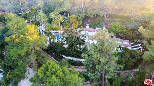 Estate compound of magical environs near the pinnacle of Outpost Estates accessed via Mulholland. Imposing gates greet visitors who are led to the residence over a hewn rock driveway to a large Motorcourt. Aquamarine Pool is surrounded by quarried Italian travertine and overlooked by the Cabana and outdoor Dining Lounge w/ fireplace. Virtual indoor/outdoor living made possible in the chef's elite Kitchen w/premium appliances & beautiful tile inlay. Unforgettable Master Suite with Roman bath & sky dome ceiling. An air of comfortable luxury pervades the living spaces -- world class resort and private home merged as one.