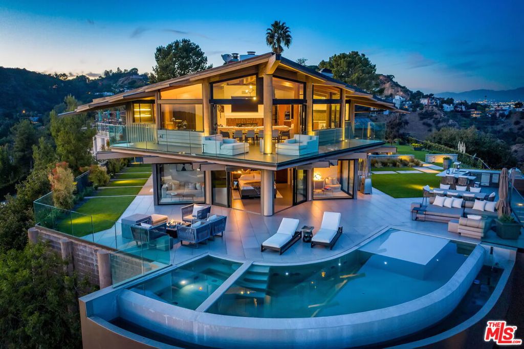Simply unrivaled. This is the sexiest, most timeless, and architecturally impressive estate in the Hollywood Hills. Designed by Harry Gesner, and set on its own promontory behind private gates, this tour-de-force overlooks some of the most iconic views in all of Los Angeles and boasts extraordinary craftsmanship with a stylistic confluence of modernity and sophistication that redefines all expectations. The top-level offers a chef's kitchen, spacious living and dining area with a custom-built bar, and separate office. Down the elevator, the owner's suite and bathroom have unparalleled views of the Hollywood Sign and the city skyline behind the infinity pool. The recording studio, detached from the main house, has been fitted with the best equipment the industry has to offer. 2-car garage and plenty of space for additional parking on the courtyard. This reimagined house celebrates the site and our 21st-century lifestyle and will be an architectural beacon for generations to come.