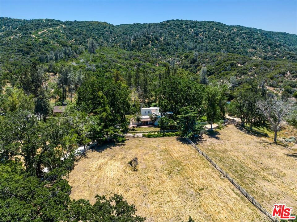 Rancho Corona Del Valle rests gently against the Angeles National Forest. Its 333 acres of pastures, aged oaks, storied 17 stall barn, and charming abodes command views across the famed Tejon Ranch. Here, located between 700,000 acres of Angeles National Forest and the 270,000 acre Tejon Ranch, you'll enjoy the expansive and private feeling of a big Texas ranch while only being one hour from Los Angeles. Rancho Corona Del Valle is steeped in history and has hosted several Hollywood legends. The ranch was long ago owned by the same family that held Westwood and the land where UCLA now stands. After its place in the Classic Hollywood film era, Rancho Corona Del Valle was a coveted quarter horse racing farm, known for horses like Top Rocket, and other steeds' illustrious wins at Los Alamitos racetrack. A yearly race in their honor continues. The main four bedroom hacienda of 4200 s.f. dates to 1883, and is jeweled with Batchelder tile, a romantic courtyard, old wooden doors, a peaceful veranda overlooking pastures and valleys, simply too many architectural treasures to name. The four guest homes ranging from 900-1800 s.f., are charming, reflecting a rich vintage ranch esthetic. In addition to the five residences there are five cottage/bungalows dotted throughout the property. On warm days jump in the swimming hole, a large water reservoir seated at the crown of the hill with breathtaking views. Ride the ranch's dirt roads and trails, gallop the old furlong race track (currently needing new footing and fencing), pick fruit from the orchard, practice riflery at the shooting range, or venture into the hills to feel the glory of nature. Ranches like Rancho Corona Del Valle are held for generations and rarely grace the market. The opportunity to buy such a piece of California history is truly rare. Buyer to verify all zoning, permits, square footage, acreage amount and land uses. Square footage is approximate and includes 5 cottages and 5 homes. Sale includes multiple APN's which total 333 acres. The barn area also offers a chicken coop, a round pen and an old roping arena of appx 250x80 ( both round pen and arena in need of new fencing and footing and have an old squeeze shoot/return alley).
