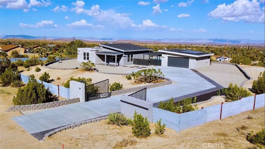 Crowning a 2.38-acre promontory in the serene heart of Yucca Valley, this 2022-crafted, single-story masterpiece is a symphony of elegance and innovation. Designed for visionaries with a taste for the extraordinary, this 3-bedroom, 2-bathroom sanctuary, unveils breathtaking vistas and an enclave of unparalleled privacy. Soaring 10-13 ft ceilings and expansive triple-pane argon windows bathe the interiors in desert light, with lustrous wood laminate floors weaving a thread of timeless chic. A 3500 kW solar system banishes electric bills, harmonized by 6-inch insulated walls and intelligent LED lighting that dances at your command. Graceful 4-ft hallways invite effortless movement, catering to every lifestyle. The gourmet kitchen, a culinary atelier, dazzles with Frigidaire stainless steel appliances, gleaming granite countertops, and a sculptural island bar, seamlessly merging with luminous living spaces for enchanted gatherings. Three palatial bedrooms, adorned with bespoke closet systems, offer serene retreats, while two bathrooms, with granite vanities, a decadent walk-in shower, a sumptuous soaking tub, and artisanal tilework, elevate daily rituals to spa-like indulgence. The private backyard is a dreamscape, where stepping stones lead to a crystalline pool, a rejuvenating spa, and an outdoor shower, framed by a courtyard with a gourmet barbecue and granite-clad prep table. Five covered patios beckon for starlit soirées or tranquil repose, while curated grounds, studded with iconic Joshua trees and lava rock accents, exude effortless splendor. A 48,000 BTU AC unit and Wi-Fi-enabled mini-split systems orchestrate perfect climate control, complemented by a cutting-edge security system. An in-home laundry suite and a 24x22 ft garage, with a Wi-Fi door, polished drywall, and climate control, marry function with finesse. Poised near Highway 247, yet a world away from urban clamor, this estate offers seamless access to Yucca Valley’s vibrant amenities. This is not merely a home—it’s a legacy of glamour, awaiting its next connoisseur. Embark on a virtual journey here and contact us to claim this celestial retreat.