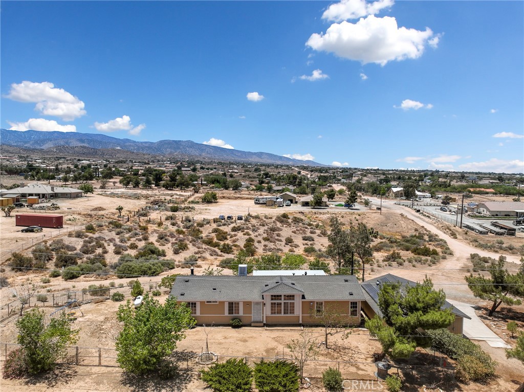 Welcome home to your escape from the fast-paced city life and immerse into your own private slice of tranquility and breathtaking views! This beautiful and clean turnkey manufactured home on Permanent Foundation boasts 3 bedrooms and 2 bathrooms with 1,664 SQFT, a 3-Car Detached Garage with concrete parking spaces, and new Septic Tank on 1.97 fenced ACRES. This home has luxury tile throughout most of the home and offers a spacious split Open Floor Plan with a large Living Room featuring vaulted ceilings, ceiling fan and a Pellet Stove area. The Family Room includes a cozy Wood-Burning Fireplace and ceiling fan. There is a separate Dining area, Kitchen with Appliances and Breakfast Bar with tiled countertop, and a Food Pantry. The convenience continues with a separate Laundry Room with Cabinets. The Master Suite has laminate wood flooring, walk-in closet and ceiling fan. The Master Bathroom features a Deep Oval Bathtub, 2 separate Vanities with additional cabinets and separate Shower. The additional 2 Bedrooms are carpeted with built in BUNK BEDS for the kids in one of those bedrooms. There is a 2nd Bathroom for family and guests. The 3-Car detached garage includes built in wood shelving and work benches. There is a covered patio with amazing mountain and desert views! Solar Panels leased on a monthly of $.01760 per kWh. This property is located just a short distance off a paved road and is also zoned for horses, so off-road enthusiasts bring your toys and animals. This property is in the popular Snowline School District and offers a great central location with quick access to town as well as the freeway for commuting making it ideal for a peaceful yet connected lifestyle. Make this your escape from the hustle and bustle of the city. Contact us today to schedule a viewing. This property is a Must See!!!