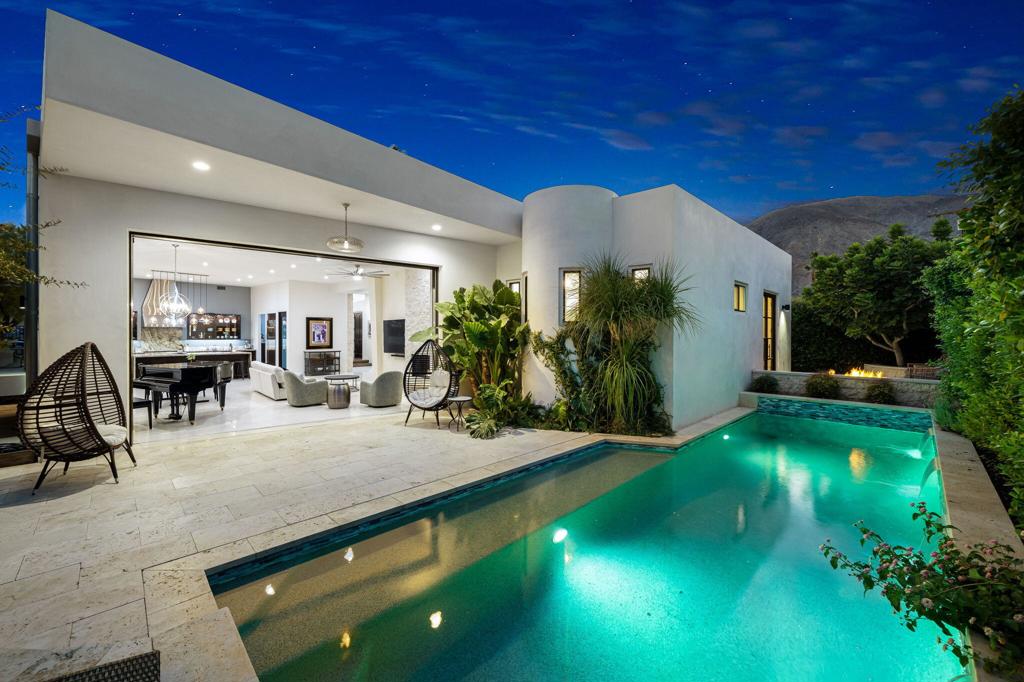 Completely rebuilt in 2020, this custom home blends modern design with organic finishes and meticulous craftsmanship. From the moment you step through the mahogany front door into the light-filled foyer, soaring ceilings, natural limestone accents, and solid 8' mahogany doors set the tone for a true desert retreat.The open-concept living space features a wine bar, stone fireplace, and oversized pocket doors that disappear to seamlessly connect indoors and outdoors. Multiple conversation areas extend to a private patio, sparkling pool with natural stone decking, outdoor shower, floating BBQ, and lush garden filled with fruit trees, grapes, olives, and herbs.The gourmet kitchen is a chef's dream, with a Sub-Zero refrigerator and freezer, six-burner Thermador range with griddle and pot filler, double ovens, dual sinks and dishwashers, expansive walk-in pantry, and a striking 5x10 granite waterfall island with seating and storage.The primary suite offers artisan iron-and-glass French doors to a private courtyard with fire feature, spa-like bath with freestanding tub, open shower, dual vanities, and two private toilets plus a custom walk-in closet. A second en suite bedroom, two guest rooms with Jack & Jill bath, a powder room, laundry, and mudroom complete the interior.Additional highlights include:XL 3-car garage (24x30) with 10' ceilings, 8' clearance doors, EV pre-wireFoam roof for added insulationNew underground plumbing, electrical, gas, and water with 200-amp serviceZoned HVAC (3 systems)Custom paver driveway and courtyardsBuilt-in angled concrete patio benchMultiple natural limestone walls and pillarsLocated at the end of a quiet street, this oversized lot offers mountain views and complete privacy, all within walking distance to El Paseo, dining, shopping, tennis, farmers market, and hiking trails.