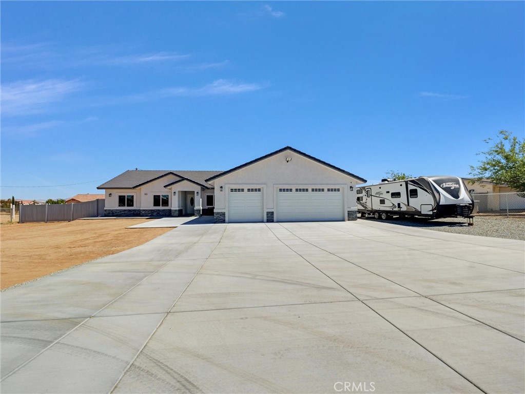Welcome Home. A beautifully crafted 2024-built home offering modern luxury, comfort, and convenience—all centrally located in one of Hesperia’s most desirable neighborhoods. This brand-new residence is ideally situated just minutes from the freeway, local schools, shopping centers, dining, theaters, fishing spots, and Victor Valley College. Step outside and you’ll immediately notice the upgraded exterior, featuring a widened driveway, extended walkway to the front door, and brand-new vinyl fencing that adds both privacy and curb appeal. Inside, an expansive open-concept floor plan welcomes you with sleek tile flooring throughout and a warm, contemporary design. The chef’s kitchen is a true showstopper, boasting European-style wooden cabinets with a high-gloss lacquer finish, quartz countertops, two culinary sinks, an enormous island with bar seating, stainless steel appliances, and abundant pantry space—perfect for cooking, entertaining, and everyday living. The living area centers around a cozy fireplace adorned with a custom stackstone facade, creating the perfect gathering space for friends and family. Retreat to the spacious master suite with vaulted ceilings, dual vanities, a walk-in closet, and a spa-like custom tiled shower with backsplash and pan. Additional highlights include an oversized laundry room with upper cabinetry, ceiling fans in every bedroom, and fully insulated garage walls for added comfort and energy efficiency. Enjoy peace of mind and lower utility bills with paid-off solar panels, a tankless water heater, and the latest energy-efficient construction technologies. Don’t miss the opportunity to own this exceptional new home in a prime location.