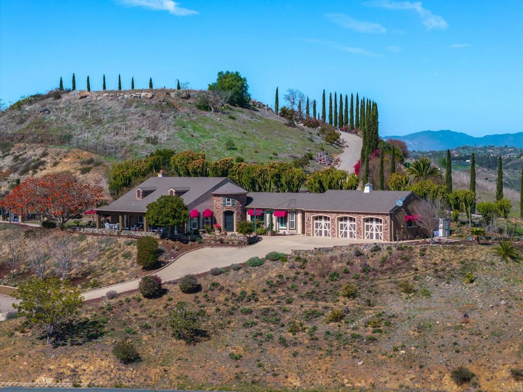 Stunning Vistas Stretching to the Sea! Panoramic views and custom-built home on over 4 acre property! This stunning home is located in the highly sought-after Bonsall area on the border of Vista. This exquisite single-story residence offers an unparalleled living experience, combining luxurious design with breathtaking views stretching all the way to the ocean. Spanning 3,059 square feet, this smartly designed home has four spacious bedrooms and three and a half bathrooms. Step inside to discover gorgeous wood flooring that flows seamlessly throughout the open floor plan, creating a warm and inviting atmosphere. From the turret entry and dining room to the kitchen, you will love the 10 ft ceilings and large windows with views in every direction, complete with plantation shutters and crown molding. At the heart of the home is the remodeled kitchen, featuring quartz counters and a butcher block center island, a large walk-in pantry, wine fridge, coffee bar, floating shelves and modern stainless steel appliances, and a family room with cozy stone fireplace.There are sliding glass doors that open up to the expansive yard. The primary suite is elegant with a coffered ceiling and fan, a huge walk-in closet with custom built-ins, a beautiful ensuite bathroom with crown molding, designer tile shower and stand-alone bathtub. There are three additional bedrooms, one with an ensuite bathroom and there's a Jack N Jill bathroom for the other two bedrooms. Outside, the property's 4.26 acre lot offers a private retreat, complete with a deck ideal for enjoying the serene surroundings with tons of fruit trees and a charming vineyard (cabernet sauvignon, merlot and chardonnay), an outdoor dining area with pergola, and multiple entertaining areas.The private road with a newer gate ensures privacy and exclusivity, making this home a true sanctuary and it is now equipped with a concrete turn-about at the top of the drive-way. Additional amenities include air conditioning, tankless water heater, whole house fan, and a dedicated laundry/mud-room area with a washer and dryer plus an exterior door, whole house water filtration system, sprinkler system, and ample parking with a spacious three-car garage. Conveniently, this home has city water - NO SEPTIC! This exceptional property combines the best of luxury living and natural beauty, making it a unique opportunity for those seeking a tranquil yet sophisticated lifestyle. Enjoy ocean breezes, vibrant sunrises and serene sunsets at this one-of-a-kind home!