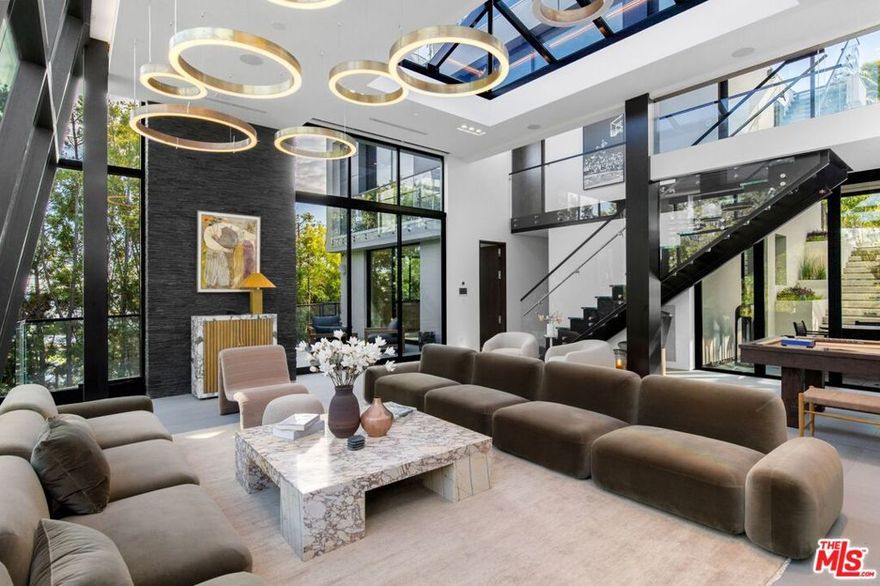 Have it all in this architectural Bird Streets compound that is set behind gates and floating just above the buzz of the city. With floor-to-ceiling glass windows throughout, open the automated shades to enjoy the iconic palm-tree lined view of the Sunset Strip that surrounds and feel the energy of Los Angeles outside. This property was made for entertaining, with Fleetwood sliding doors that pocket fold in true indoor-outdoor California fashion and multiple levels to host guests both indoors and outdoors on the various terraces or on the 3,500 square foot, 180-degree view rooftop deck. Additional features include 7,332 square feet of living, five bedrooms, nine baths, a dedicated club space with theater, elevator, four-car garage, Control 4 system and incredible resort-style yard and pool area set amidst the LA backdrop and city lights. A perfect sanctuary with access to everything.