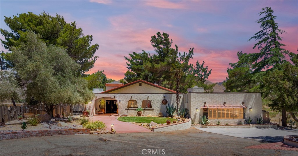 Truly One-of-a-Kind Spanish-Style Estate on Over 4 Acres with Guest Suite & Astounding Views! Experience rustic elegance and exceptional versatility in this beautifully upgraded 4 bedrooms, 3 baths custom home with nearly 3,000 sq ft of living space on over 4 acres. This Spanish-style estate is perfectly suited for multi-generational living, entertaining, or those seeking a self-sustaining lifestyle with comfort and charm throughout. The showstopper here is the expansive family room with its cathedral beamed ceiling, massive picture windows, wood burning stove with brick accent built in seating as well as a wet bar area. The remodeled kitchen features rough-edge granite countertops, a hammered copper farmhouse sink, stacked stone backsplash, Bosch double oven, and under cabinet lighting. The formal dining area sits fine beneath the loft area and is framed with beautiful carved wood. With details such as the Knotty pine solid wood doors, multiple skylights, plantation shutters, and French doors throughout, this property exudes timeless warmth and style. The expansive game room offers its own HVAC system and a built-in safe. A separate mother-in-law suite provides privacy for guests or extended family. The laundry room includes a utility sink, built-in drying racks, and a beautiful custom wood and glass door. Another unique room to note is the cigar room just off of one of the bedrooms. Outside, enjoy a grapevine-covered pergola, a deck with outdoor kitchen, sparkling 9-ft deep pool, and so many secret garden sitting areas. Additional features include a detached flex space complete with electricity perfect for a studio or a home office, fenced RV area, shed, dog kennel, and electric security gate offering the utmost privacy. Bonus upgrades: 2 septic systems, home is on its own well and comes with two separate 2500 gallon water tanks with fire hoses. Also included is a rustic wine fridge and finished garage. All plumbing and wiring in place for a separate Generac generator.