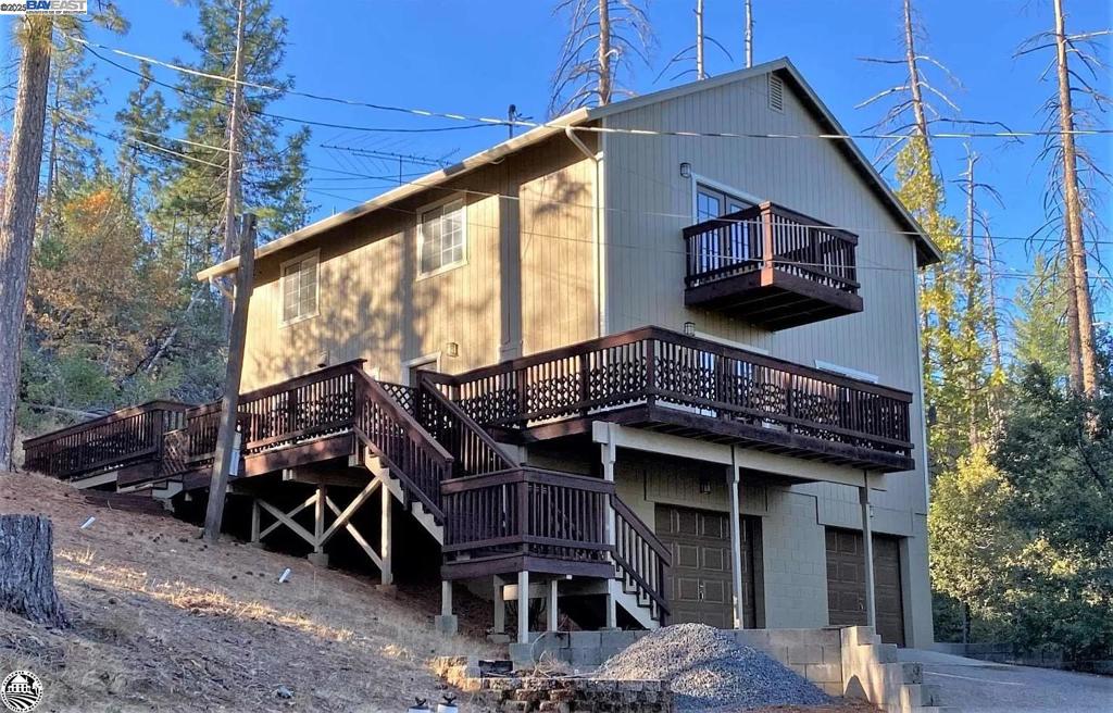 Just one mile from town with stunning mountain views — and no HOA dues! This lightly used vacation home offers 3 bedrooms and 3 full baths, featuring a soaring two-story living room with a propane stove and French doors opening to a massive wraparound deck. Enjoy spacious dining areas, abundant kitchen counter space, and a convenient breakfast bar. A separate laundry room with tile floors and pantry cabinets sits just off the kitchen, with an interior stairway leading to the impressive garage below. The oversized garage measures approximately 30' wide by 35' deep (over 1,000 sq. ft.) and can potentially fit up to 4 cars in tandem, with sturdy concrete block walls on three sides. The large master suite boasts French doors to a private deck and a walk-in closet. Additional features include five ceiling fans, double-pane windows, and mini/vertical blinds throughout. Recent upgrades include new laminate and tile flooring in the great room, new gutters, freshly paved driveway with retaining wall, and a serviced septic system. A perfect blend of comfort, space, and views — ready to welcome you home.