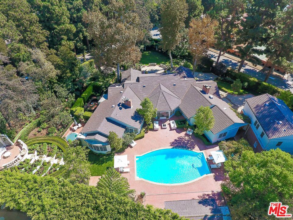 Exceptional, Stunning and Private Gated Paul Williams Traditional single story estate on just under an acre of magnificent park like grounds on a fabulous corner lot location North of Sunset. Marble entryway leads to formal living room and family media room with fireplace and bar all opening onto patio, gardens and large mosaic tile pool. Elegant Dining room seats 20, formal breakfast room, gourmet kitchen with Brazilian granite countertops, custom cabinetry, Wolf range and s/s appliances. Romantic master suite with dressing rooms, steam shower & spa tub opens to private outdoor spa tub. 3 additional en-suite bedrooms. Cabana includes fully equipped gym, bath and kitchen with BBQ. Guest house/office with bath, two bedroom staff quarters, motor court area for ample parking and two car garage.
