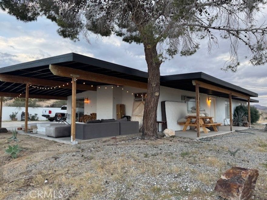 This place has an amazing story and many cool aspects. There is a main house and a back house, (two adjoining lots sold separately but could be purchased together)included with this sale. The main house has 3 bedrooms and 2 bath with brick fireplace, central heat and AC (dated) with additional Evap cooler, separate indoor laundry and mud room exit/entrance, massive windows with views for days, expansive carport and oversized covered patio, mature trees and landscape throughout the property. There is new asphalt leading up to the property and several hundred square feet of concrete outside for more curb appeal and less dirt and sand indoors. Solar panels have been installed and are saving the homeowner money each month and is on a lease, that will need to be transferred or negotiated in the purchase and paid off at closing.  The detached 1 bedroom unit has been fully remodeled with a full kitchen, heating, mini split, dining and living space with a separate bedroom that can fit a King bed with a 3/4 bathroom. It's a wonderful add to an already existing 3/2 house next to it. Very private and tremendous views from almost any window or door. It sits atop a hill that has many unobstructed views of the mountains, valleys, homes, sunsets and sunrises! Truly one of the best properties at this price in 29 Palms! If that was not enough, two additional parcels one on each side of the property can also be purchased. You can build your dream homes or add ADU's and garages depending on your vision and approval through the City. There is Soooo much potential!!!!! (other two lots - APN: 0617-021-11 located to the right of the property from street view and its 19,600 sq feet. 0617-031-14 on the left side of the driveway pulling in from the HWY and its 23000 sq feet. More info on the parcels in the supplements) Professional photos by Dec 15th.