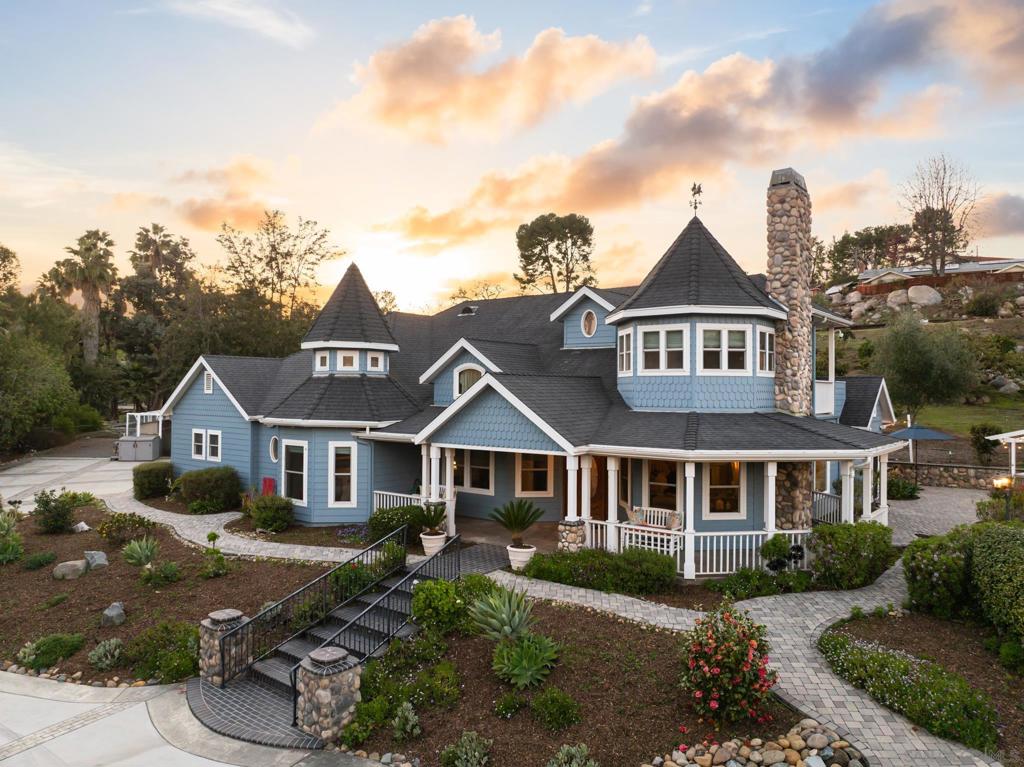 Nestled on 1.6 private acres in the exclusive Mt. Helix area, this custom-built Victorian-styled farmhouse seamlessly blends old world elegance with 21st century comforts. As you pull up the circular driveway to the main entrance, the tranquil charm of the wrap around porch will invoke visions of sunny afternoons sipping lemonade to the sound of chirping birds. Stepping inside, the expansive Great Room, with its rich hardwood floors, soaring ceilings, and a stone fireplace provides a feeling of coziness & warmth. The Chef’s Kitchen, featuring custom cabinetry, antique-styled appliances, and a Butler's Pantry, showcases high-quality craftsmanship. The main floor Primary Suite offers plush custom carpeting, a private patio, a spacious walk-in closet, with a stunning ensuite bath featuring 20-foot ceilings, a clawfoot soaking tub, and antique-styled vanity. 2 additional bedrooms complete the main floor. Upstairs, a full-floor loft includes a fireplace, vaulted ceilings, and a balcony. The resort-style pool & spa area, with a stone fireplace, outdoor kitchen/bar, and pool house, is ideal for entertaining. The separate 2-bedroom Guest House, with its own garage, laundry room, vaulted ceilings, and private yard is perfect for multi-generational living, overnight guests or rental income. Both residences have central air/heat, tankless water heaters, solar power, & EV charging. The property is gated & includes RV parking, a chicken coop, ten varieties of fruit trees, a seasonal creek, security cameras & Tesla Powerwall for the main house. Close to freeways/shopping
