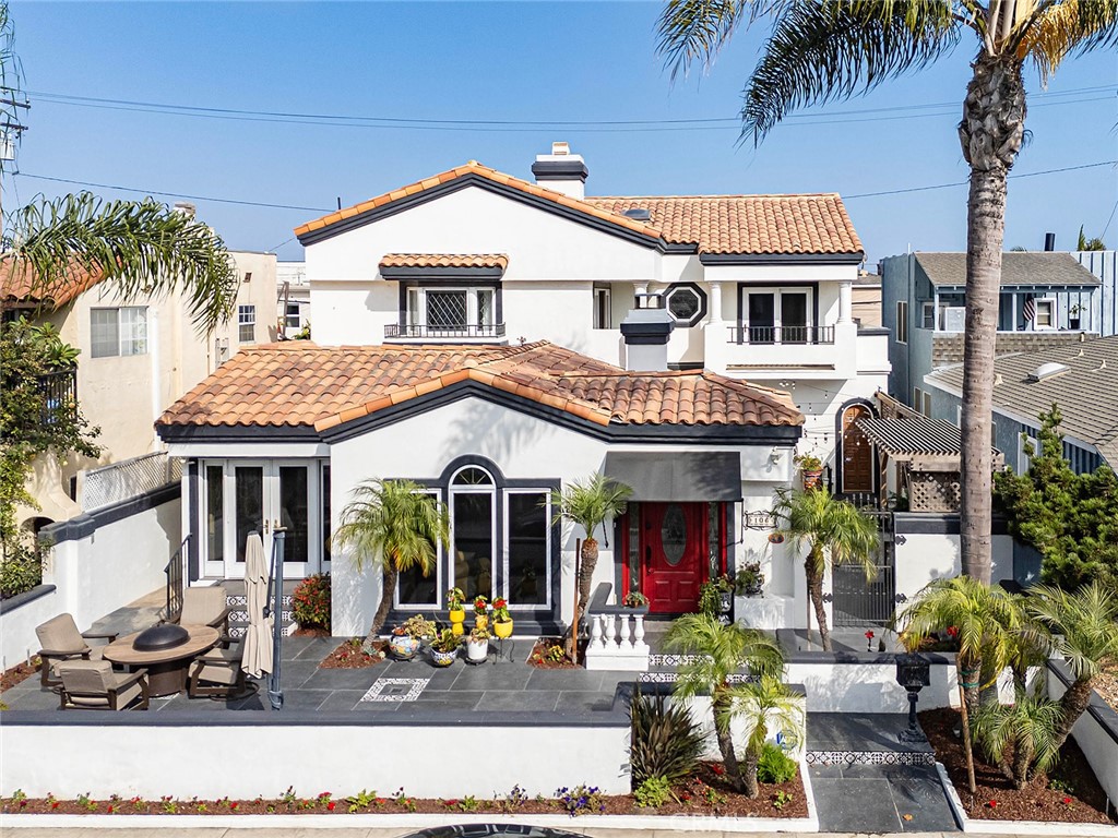 Experience the ultimate in coastal living with this stunning custom Mediterranean estate on a rare lot and a half in Belmont Shore—just steps to Alamitos Bay, one block from the ocean, and a short stroll to 2nd Street. Designed to maximize both vibrant entertaining spaces and private retreats, the expansive front dining patio is perfect for lingering with a glass of wine while greeting neighbors, while the oversized private side patio—with built-in grill, outdoor kitchen, and fireplace—offers the perfect setting for al fresco dining and gatherings under the stars. A striking inlaid glass entry door opens to an expansive living room with open-beamed ceilings, a distinctive brick fireplace, large picture window, hardwood floors, and built-in shelving flanking the arched entry to the formal dining room. From here, a wall of folding doors connects seamlessly to the side patio, blending indoor comfort with outdoor charm. The remodeled kitchen features granite counters, Viking appliances, custom cabinetry, and abundant storage, along with a charming breakfast room that opens to the front patio—keeping you connected with guests while you cook. A versatile downstairs bedroom, family room, or office has its own private entrance with steps to the bay. The remodeled three-quarter bath with unique tile work, a large laundry room with storage, and an oversized attached two-car garage with parking pad complete the first level. Upstairs, the primary suite is a serene retreat with a fireplace, bay window with beveled glass, private balcony, and a dream-worthy walk-in closet with custom cabinetry. The remodeled spa bath offers a standalone tub, walk-in shower, dual sinks, and peek-a-boo bay views. The guest suite enjoys a newer three-quarter Jack and Jill bath and its own balcony to catch ocean breezes, while the third bedroom offers its own bay views. Notable upgrades include three remodeled bathrooms, folding side doors, built-in BBQ/outdoor kitchen, new garage door system, outdoor tile, HVAC system, and a high-tech WiFi router. Blending refined design, modern comforts, and an unbeatable location, this is more than a home—it’s a coastal lifestyle you’ll treasure.