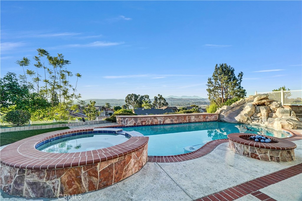 Experience the best of California living in this stunning two-story single family home offering over 3,030 sq. ft. of living space on a generous 10.290 sq. ft. lot size. Five spacious bedrooms and three updated bathrooms, one bedroom and a bathroom are conveniently located on the main floor offering flexibility for guest or home office. This move-in ready residence combines comfort, elegance and panoramic views. From the kitchen and adjoining family room, enjoy breathtaking views of the city lights and mountains--an ever changing backdrop that can also be admired from the expansive primary suite. The primary bedroom features a large picture window that perfectly frames the scenery, providing a serene start and finish to every day. The private backyard is a true retreat, featuring a sparkling pool and spa, a firepit, and stunning man-made rock waterfall, all designed for relaxation and entertaining. Inside. downstairs, rich wood flooring in living & dining room and family room with a thoughtful floorplan add warmth and character throughout this beautiful home. The spacious game room complete with a pool table, offers a perfect space for fun and gatherings. A three car garage and long driveway provide ample parking and convenience. This gorgeous home is a rare find--full of charm, modern updates, and spectacular views. Close to shopping, top rated schools, fine dining, freeways such as 91, 55 and 22. Welcome home.