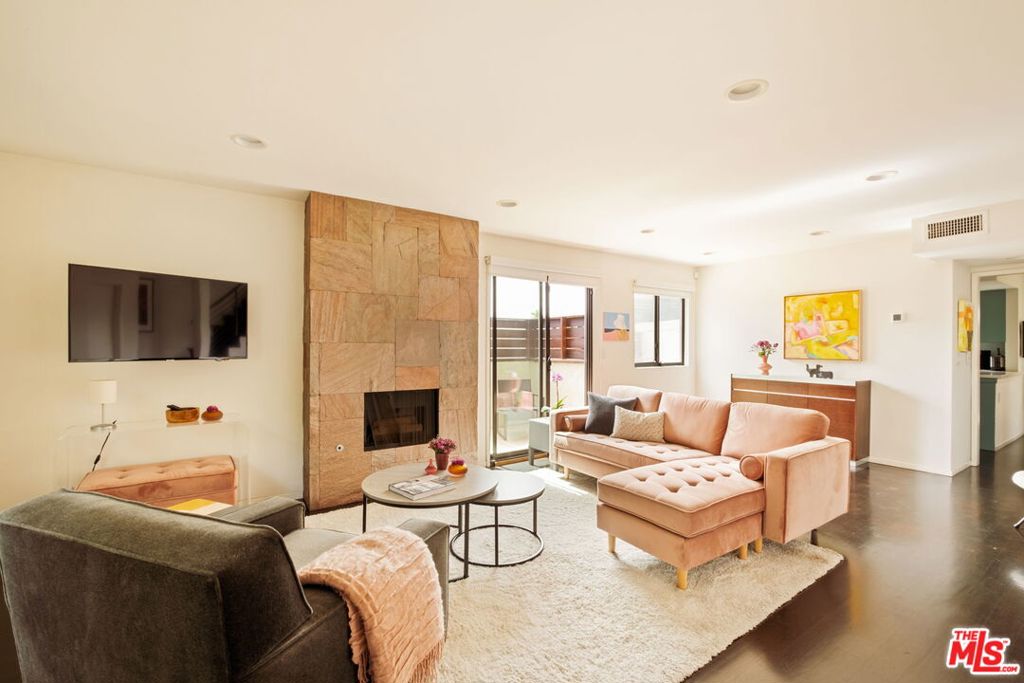 This bright and inviting walk-up townhouse lives like a private home, with no neighbors above or below, just one shared wall, and its own private two-car garage. A direct-entry porch opens to a sun-filled living room with a gas fireplace, space for dining, study, or sitting area, and access to a private patio. The great room flows into a large, fully updated kitchen with colorful cabinetry, stone countertops, and stainless steel appliances, plus an adjacent dining area and access to a second patio for outdoor lounging. An updated powder room completes the main level. Upstairs, two spacious bedrooms include a primary suite with remodeled bath and balcony, along with a second updated bath and a convenient laundry area. Additional features include three exposures (south, west, and east) that fill the home with natural light, dark hardwood floors, recessed lighting, crisp white walls, central heat and air, and excellent closet space throughout. The private garage below provides secure parking, extra storage, and direct unit entry. Move-in ready and located in an intimate five-unit building in Sunset Park, just blocks to Bob's Market, Will Rogers Elementary, neighborhood parks, gyms, and dining, and only eleven blocks to the beach. HOA dues are $675/month and include earthquake insurance, water, sewer, and trash. A modern yet warm retreat, thoughtfully designed to maximize space, comfort, and style.