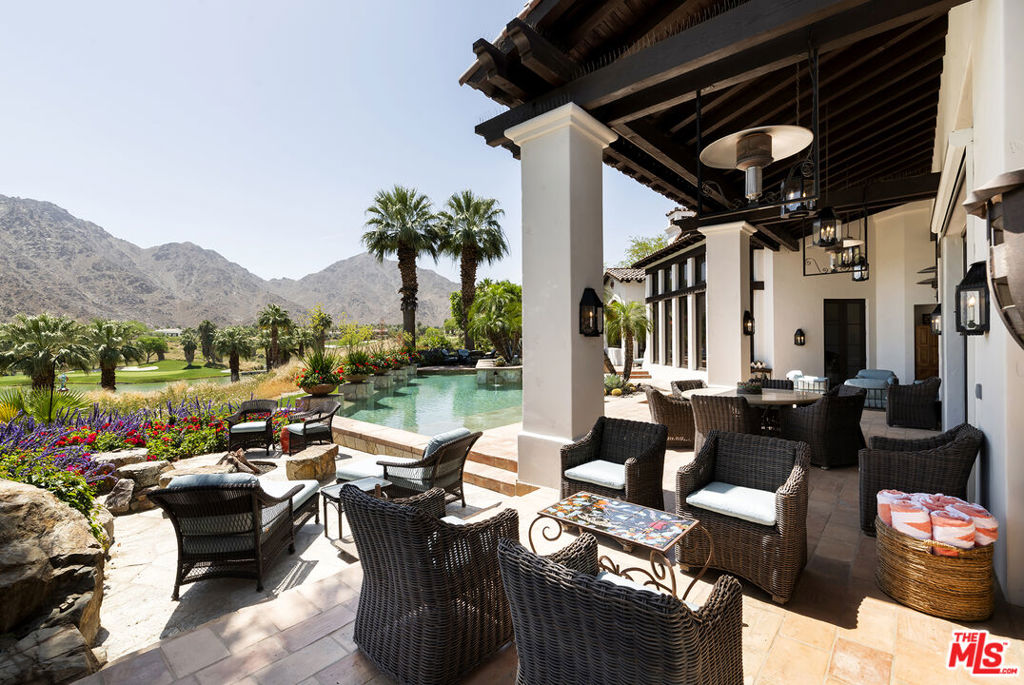 Indulge in the epitome of luxury living with this breathtaking mountain and lake-view estate, uniquely situated in a premiere position above the 7th and 8th holes of the prestigious Tradition Golf Club. Designed by renowned architects, Hunt Hale Jones, and a world-class designer, this Montecito-style masterpiece has been meticulously cared for and updated to offer the pinnacle of sophistication with a resort-like allure. Entering through antique gates, you are greeted by manicured flower beds and a spacious courtyard adorned with a charming fireplace. Also, convenient and quick access in and out of the club with the property's prime location. The grandeur continues as you step inside the elegant foyer and expansive living room with spectacular Mountain Views. Wood-beam ceilings, striking Saltillo tiles, an antique European fireplace, and the adjacent formal dining room, create an inviting ambiance for relaxed gatherings. The kitchen is a chef's delight, boasting Viking appliances, an oversized island, and a convenient butler's pantry. Retreat to the utterly luxurious primary suite, boasting panoramic views, dual closets, vanities and a marble shower. This is Seamless indoor/outdoor living, perfect for entertaining. Infinity edge pool, with lap lane and jacuzzi, plus an outdoor alfresco kitchen and living space, complete with a cozy fireplace, heaters, and water misters give an ideal setting to savor the majestic desert landscape. To top it all off, your guests will relish in the comfort of a detached casita with a kitchenette. Spacious three-car garage and large golf cart bay. An incredible one-of-a-kind oasis, this estate presents a truly elevated lifestyle.
