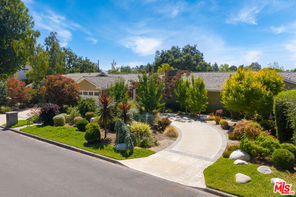At 1009 Jeannette Avenue, you'll awaken to the gentle sounds of birds singing, watch sunsets you're certain were painted just for you, and fall asleep under the stars in this night sky neighborhood. Welcome to your private sanctuary in the bucolic Conejo Oaks neighborhood of Thousand Oaks. This beautifully updated, single-level custom home has a thoughtfully designed floorplan perfect for both family living and entertaining. The sense of serenity starts at the curb as you walk through a professionally designed front yard landscaped with a beautiful palate of drought-friendly trees and foliage that offer color all year round. Enter into a wide foyer that opens on one side to a formal living room and the other to a luxurious office. The living room flows seamlessly into a large dining room framed by floor to ceiling windows and French doors that open onto a patio. The kitchen is a chef's dream. The functional layout offers easy access to the oven, refrigerator and two sinks, making meal prep both efficient and enjoyable. Two islands provide ample prep space as well as a gathering area for casual dining at the counter. The kitchen is appointed with high-end appliances including a built-in wine refrigerator and espresso maker, as well as a spacious walk-in pantry. An informal dining room flows into a large family room with vaulted ceilings, a wall of custom built-in bookcases and cabinetry, and tons of natural light. The primary suite and two other bedrooms, both with en-suite bathrooms, are located on one side of the home. The luxurious primary suite features two large walk-in closets, a custom vanity with quartzite countertops, large spa-like bathroom with double vanity, a huge shower, a tub that overlooks the greenery outside, private lavatory, and French Doors that allow you to step out onto the main patio. The fourth bedroom and bathroom is privately situated within the home. The backyard was designed for nature lovers, entertainers and swimmers alike. The large patio on the upper level, accessible from the dining room, kitchen and primary suite features a built-in grill, outdoor fridge and cabinets, as well as a fire pit perfect for enjoying those custom sunsets. Step down a flight of stairs to an extra-long pool where you can relax under the pergola after an invigorating swim or enjoy a homemade pizza from your very own wood burning pizza oven! The landscaping in the backyard is filled with natural, indigenous plants that attract a plethora of birds, butterflies and a flutter of hummingbirds. The backyard is primed and ready for your vision to customize it even further to your desires. Additional features of this special home include walnut wood floors throughout, solid walnut doors, a colorful outdoor hideaway with cafe lights, a dog run, finished garage with epoxy floor and ample cabinetry, an anchored outdoor storage shed and room on the side of the house for an RV.