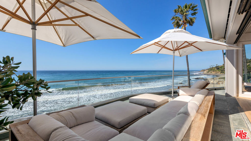 The Encinal Beach House - Located on a stunning stretch of the Malibu coastline where properties are rarely offered for sale, this beachfront home sits in a small pocket cove known as El Sol surrounded by large bluff properties and very few other homes directly on the sand. Nestled in a low bluff above the beautiful Pacific Ocean with direct access to one of the most private and coveted beaches in Malibu. This property is on a private gated street down off of PCH with an incredible oceanfront location where tranquility and an indoor/outdoor lifestyle are combined. Top of the line finishes and fixtures, hardwood floors throughout, walls of glass, high ceilings and open spacious living areas. The interior spaces of the home are impeccably detailed and offer large glass doors in all rooms that open to expansive patios and balconies allowing the ocean breezes in. The primary suite is on the oceanside with a fireplace, large walk-in closet and a spa like bathroom with bath tub and steam shower. Three additional bedroom suites that offer sophistication and style while being incredibly comfortable for your guests. Outdoor fire pit with built-in seating area, hot tub, shower and sauna set among the perfectly landscaped grounds make the perfect setting for relaxing and watching the surf during the day or the sunset. Living in a location like this where you see the rugged bluffs meet the sea and the dolphins playing out front is so rare and special!