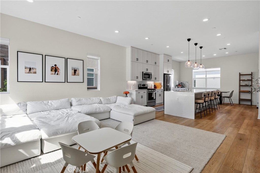 Perched in Anaheim’s Platinum Triangle with premium pool views, this 2021-built end-unit home features 4 bedrooms, 3.5 bathrooms, and 2,160 sqft of bright, thoughtfully designed living space. From the rooftop deck to the gourmet kitchen, every detail has been crafted for modern comfort, entertaining, and effortless living. The entry level features a private bedroom with a full ensuite bath, ideal for guests or multigenerational living. The second floor is the heart of the home, where an expansive great room is bathed in natural light from walls of windows and soaring ceilings accentuated by recessed lighting. The gourmet kitchen is a chef’s dream, with ceiling-height shaker cabinetry, a waterfall-edge quartz island with bar seating, quartz backsplash, ceramic farmhouse sink, and a spacious pantry. A bright breakfast nook, powder room, and indoor laundry closet complete this level. Upstairs, the primary suite is a serene retreat, featuring dual sinks, upgraded porcelain tile flooring, a subway-tiled shower, and a large walk-in closet. Two additional well-sized bedrooms share a beautifully appointed hallway bath. The fourth-floor rooftop deck is the ultimate entertainer’s dream - perfect for hosting friends, relaxing with family, or enjoying panoramic city views and Disneyland fireworks. Thoughtful upgrades elevate every level of the home, including LVP flooring on the main floor, roller blinds throughout, solar-ready rooftop, a water filtration/softening system in the kitchen, and strategically placed outlets for wall-mounted devices. A 2-car garage with EV charging and side storage space completes the property. Residents enjoy a resort-style community pool, while the location puts you just minutes from Disneyland, Honda Center, Angels Stadium, the up-and-coming OCVIBE district, and major freeways. This home seamlessly combines modern finishes, exceptional upgrades, and unmatched convenience in one of Anaheim’s most vibrant neighborhoods. Schedule your tour today!