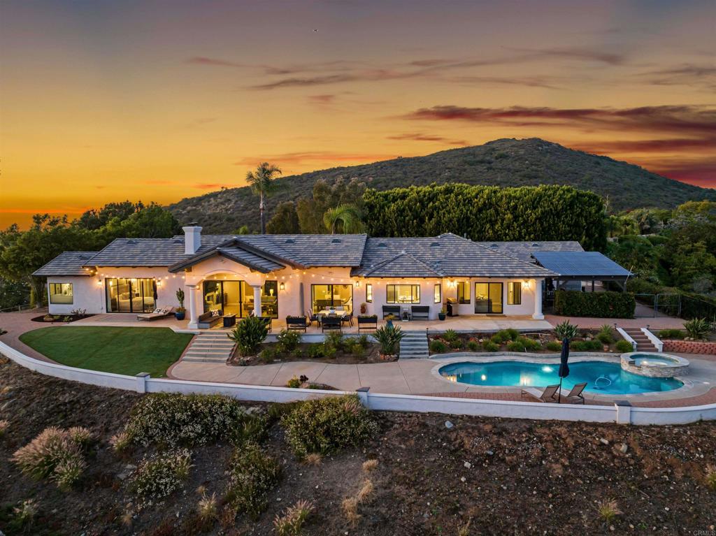 Stunning Single-Level Vista Estate with Panoramic Ocean Views, Resort-Style Pool, and 4-Car Garage – Perfect for Multi-Generational Living! Welcome to 1966 Las Lomas, a one-of-a-kind, fully renovated forever home nestled in the scenic hills of Vista. Privately situated within a gated community, this expansive single-level estate welcomes you with a custom-designed gated driveway with elegant lighting, offering privacy, curb appeal, and a grand sense of arrival—along with dramatic ocean and sunset views from nearly every rear-facing window. Thoughtfully redesigned with modern finishes and high-end touches throughout, this 5-bedroom, 3.5-bathroom home offers a beautifully balanced floor plan with 3,562 square feet of single-level living. Soaring ceilings, abundant natural light, and open sightlines greet you the moment you step through the door. Ocean views stretch from Carlsbad to Catalina by day, while evenings bring a canvas of twinkling lights from the valley below. The home’s layout is ideal for multi-generational living, with distinct bedroom wings that offer both privacy and flexibility. The spacious primary suite and adjacent secondary bedroom (currently used as a home office) sit on one side of the home, while the opposite wing features three additional bedrooms—one with its own private bath, and another oversized room with backyard access that functions beautifully as a second family room, guest quarters, or teen lounge. The entertainer’s kitchen includes dual Quartz islands, premium KitchenAid appliances, a wine fridge, beverage sink, filtered hot and cold water, and custom cabinetry. It opens directly to the great room, where 16-foot sliding glass doors create a seamless flow between indoor and outdoor living. Meander outside to your resort-inspired backyard, where a rebuilt saltwater pool and spa take center stage. With new tile, plaster, coping, Pentair equipment, and solar heating, the pool area was designed to maximize the panoramic views and create a true destination experience. Additional highlights include a 4-car garage (3-car plus separate 1-car), photovoltaic solar system with two LG batteries and new inverter, 2021 roof, full fire sprinkler system, generator-ready electrical, pressure-boosting water system, and a fully level layout with wide hallways and high end easy care plank tile flooring. There’s no HOA or Mello-Roos. More and more buyers are discovering the charm and convenience of Vista, one of North County’s most up-and-coming communities. The city’s revitalized downtown offers a growing list of breweries, restaurants, coffee shops, and entertainment venues—all in a walkable, welcoming setting. Locals enjoy mild, sunny weather year-round, and the city’s proximity to the coast (just 30 minutes to the beach) makes it a top choice for those seeking the perfect balance of inland space and coastal access. Vista is known for its laid-back vibe, community events, and scenic surroundings that make everyday living feel like a retreat. Don’t miss your chance to own this rare single-level estate with unbeatable views and flexible living—schedule your private showing today!