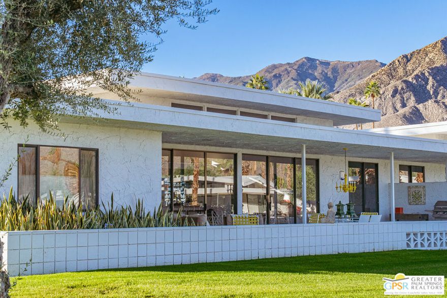 In South Palm Springs iconic Canyon Estates, this architecturally significant Charles Du Bois residence captures the best of 1970s desert modernism with clean lines, clerestory windows and seamless indoor-outdoor flow. Sited on a serene interior street, this home enjoys a north facing orientation that frames the San Jacinto mountains in full dramatic scale from the largest private patio in the community. Soft morning light, shaded afternoons, and glowing sunsets create an outdoor living experience that is unmatched in the neighborhood. Inside, the generous floor plan offers two large bedrooms, three bathrooms and a large den or office that can also become a bedroom, providing excellent flexibility for modern living. The expansive great room encompasses the living room, dining room, and a chic full-size wet bar all opening through walls of glass to the terrace, drawing the mountain views directly into the home. The kitchen and breakfast room elegantly respect the original plans of the architect and open onto the terrace as well. The primary suite is generously proportioned with an oversized bath, dressing area, multiple closets and direct access to the terrace, offering mountain views from the moment you wake up. Canyon Estates offers a true resort style living experience with an executive nine-hole golf course, fifteen pools, twelve spas, a clubhouse, fitness room and tennis courts. HOA dues of $925 per month include exterior landscape, exterior building insurance, exterior paint, pest control, premium cable and internet. The community sits just minutes from Indian Canyons and Andreas Hills, providing immediate access to some of Palm Springs most beautiful hiking trails and natural preserves while being just minutes from downtown's shopping, dining, and entertainment. Balancing architectural pedigree, expansive outdoor living and a premier South Palm Springs location, 2324 Camino Vida is a unique and timeless offering.