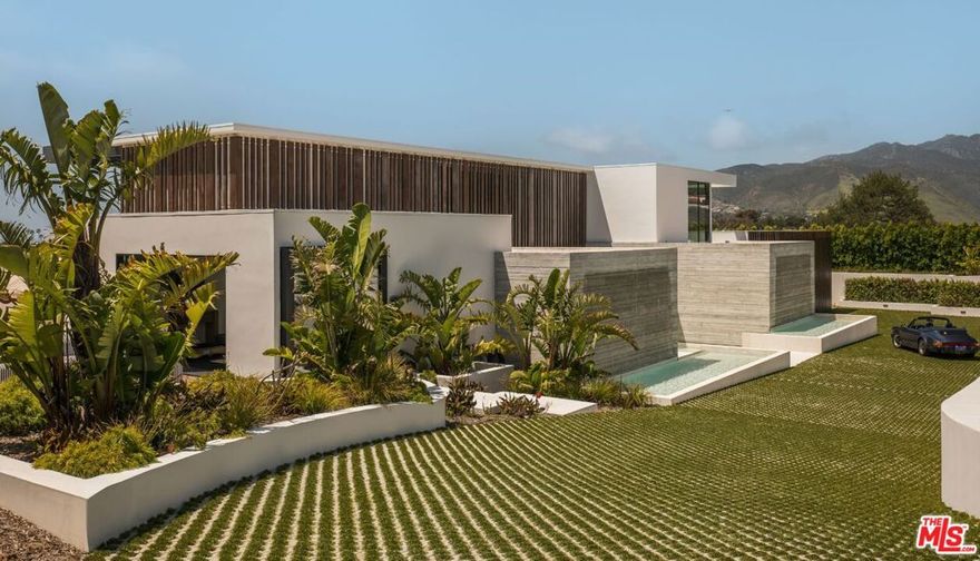 Introducing TerraLume, Malibu's newest iconic estate nestled within the ultra-exclusive Point Dume enclave. Spanning 2.25 acres of pristine grounds with commanding panoramic ocean views, this 8,500 sq ft, 6-bedroom, 8-bathroom masterwork offers the pinnacle of architectural sophistication and resort-style living. A harmonious fusion of contemporary design and materials, TerraLume features board-formed concrete walls, curated stone finishes, and floor-to-ceiling disappearing glass doors that seamlessly blend indoor and outdoor living. Highlighting Malibu's legendary sunsets at every turn. Enter through a tranquil lagoon to a grand 8x10 custom copper pivot door, leading into a dramatic double-height entry and voluminous open spaces.  Every detail has been hand-selected for its artistry: handmade chandeliers, handcrafted wood louvers, etched copper walls, and a bespoke Italian kitchen. The floating staircase ascends to a private upper level featuring an opulent primary suite with two fireplaces, a spa-inspired bath retreat with hand-carved marble vanities, a sculptural stone soaking tub, and a steam shower framing unforgettable ocean vistas. Outdoor amenities rival world-class resorts: a covered outdoor kitchen and bar, 70-foot pool and spa, detached guesthouse, fitness studio with sauna, and gated motor court with parking for up to 20 vehicles. Enjoy private access to Little Dume Beach through the coveted Riviera III beach key.