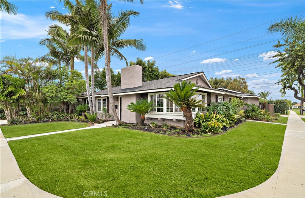 Sprawling, upgraded & expanded single-level home on a 7,800 SF interior corner lot that backs to the neighborhood park, boasting lovely curb appeal w/wrap-around tropical landscaping, new roof (2022), 2 custom entry doors, and all dual pane French-style windows. This stunning home provides over 2,000 SQFT of versatile living space because the 460 SF garage was converted (unpermitted) into 3 rooms - an office, an inside laundry room, and a bonus room (could be 4th bedroom), plus a permitted extension of the existing family & dining rooms. Inside, the open-concept layout offers both a grand great room and an elegant formal living room with rich hardwood flooring, recessed lighting, raised panel doors, & ceiling fans. The formal living room features a charming fireplace and wraparound French windows with an extended display ledge—perfect for plants, décor, or simply soaking in abundant natural light. The expansive great room seamlessly blends the family room, dining area, and gourmet kitchen into one inviting space. The dining area is set beneath a Solatube skylight and has built-in cabinets & buffet counter, while the adjoining family room offers views of the backyard and features charming white floating display shelves and a built-in hutch/desk. The chef’s kitchen boasts a massive granite-topped center island with bar seating, pendant lighting, and abundant storage—including under-counter microwave & wine rack. Rich Cherrywood self-closing cabinetry w/pull-outs, built-in desk niche & décor shelving, & Professional-grade stainless appliances—including a 6-burner gas range w/vent hood—make it a dream for cooking & entertaining. Step outside through French doors to your tropical backyard oasis, large enough to host a wedding, complete with a park-like lawn, covered patio, outdoor fireplace, stacked stone exterior accents, and lush foliage for privacy. A large storage shed is included. The double RV gates and RV driveway offer potential to rebuild a garage while still keeping current garage as living space. The primary suite features an organized closet, French doors to the backyard, and a stylish ensuite bath w/slate-style tile floor, walk-in shower & pedestal sink. 2 additional bedrooms share a beautifully upgraded & expanded in 2017, hall bath w/antique-style vanity, vessel sink, mosaic tile floor, and a tub/shower w/tile surround. New water heater '24, plumbed for A/C in '23. Close to top-rated schools, shopping, dining, and just a short drive to the beach.