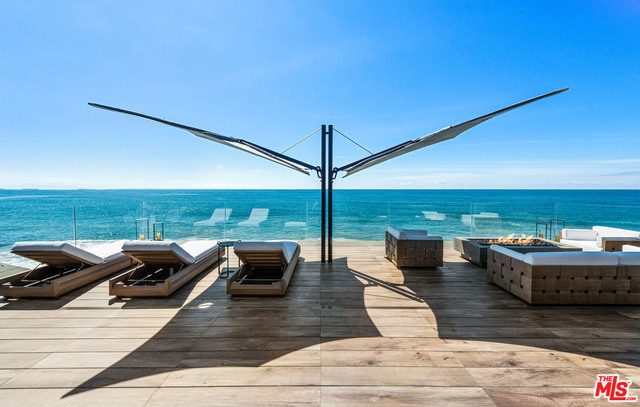 Spectacular 3-story, newly renovated Carbon Beach home with panoramic ocean and white water views from Palos Verdes to the Malibu Pier, & beyond. Gated/private with FP and waterfall courtyard entry, with beach access, the main level features sitting/dining area with FP, chef's kitchen, glass wine closet, and auto Fleetwood doors to deck with beach access, home theater, en-suite bedroom, & 2-car garage. A floating glass/wood staircase or a pneumatic elevator that services all levels, ascends to the 2nd level to the ocean view owner's retreat w/FP, yoga/office area, auto doors to a deck w/fire pit, & a luxe bath w/steam shower, tub, & custom closet, plus a den w/FP & a floor-to-ceiling glass room gym, & 2-en-suite bedrooms. The 3rd-level offers the ultimate in outdoor-indoor ocean view living w/a family room w/FP & sliders that open to an entertainer's dream w/fire pit table, BBQ island, hot tub & sitting area w/fire pit, bdrm, & shower bath, all accessed by stairs from courtyard entry.