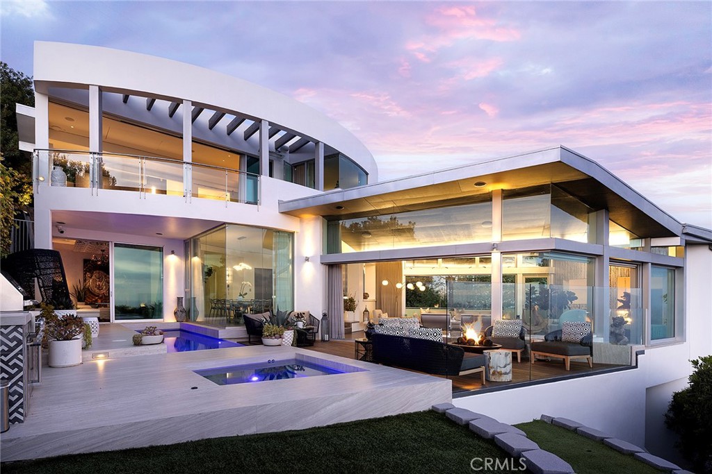 Architecturally Significant Ocean View Modern In the Sky – Laguna Beach Perched atop one of Laguna Beach’s most coveted vantage points, this architectural tour de force masterfully designed by acclaimed architects Horst Noppenberger and Paul McLean and built to exacting standards by Prestige Builders redefines coastal luxury living. Showcasing unparalleled 180-degree ocean views, this gated estate captures breathtaking vistas spanning the full coastline, both north and south arguably the finest in all of Laguna Beach. A bold expression of contemporary design, the residence rises nearly 60 feet from floor to rooftop, evoking a sense of floating above the ocean below while offering complete privacy and jaw-dropping views from every room. The dramatic entry sequence, defined by monumental vertical white concrete walls and a stone driveway that curves to a crescent-shaped entry, sets a striking tone of sophistication upon arrival. Designed to maximize the immersive ocean experience, the interior blends a refined material palette of custom hand-troweled epoxy flooring with hand-finished oak, creating a warm, minimalist interior that flows effortlessly throughout. Floor-to-ceiling glass and automated disappearing Fleetwood doors seamlessly connect expansive interiors with sun-soaked terraces and a negative-edge pool and spa framed in stone. Elevating the art of home entertainment, the residence features a state-of-the-art theater, full bar, and temperature-controlled wine cellar creating the ultimate environment for hosting friends and family. At the heart of the home, the gourmet kitchen features Poggenpohl cabinetry, a glowing Cristallo quartzite island, Miele and Gaggenau appliances, and a fully equipped butler’s kitchen blending function with refined design for both everyday living and elevated culinary experiences. Smart home technology powered by Control4, including automated lighting, climate control, and a comprehensive security system, enhances ease and peace of mind. Crowning the home, the penthouse-level primary suite spans the entire fourth floor, offering sweeping ocean views, dual walk-in closets, Poggenpohl cabinetry, and an oversized soaking tub for two. An oversized 3.5-car garage, private elevator, direct access to preserve trails, and proximity to Newport Coast, Fashion Island, and John Wayne Airport round out this exceptional offering.