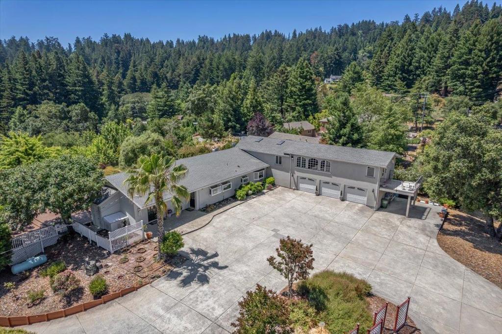 Elegant home close to town on a sunny acre with views! This 4 spacious bedroom, 3-bathroom home is a haven of light and style. Formal entry with stone tile leads to inviting living room, featuring high ceilings and abundant windows and views, complete with new carpets. The gourmet kitchen boasts granite countertops, a center island with a breakfast bar, stainless steel appliances, and garden windows framing mountain vistas. Formal dining room, pantry and laundry area. Two primary bedrooms, one is a private retreat with exposed wood beams, distressed wide plank flooring, and a gas fireplace, enormous walk-in closet with built-ins and a luxurious bathroom with a sunken tub, and a shower with a stunning granite backsplash that leads to a private deck for morning coffee. Back yard has expansive Trex deck with breathtaking mountain valley views, grassy area, a large side yard with garden and horseshoe pit. Car enthusiasts will love the attached 3-car garage, carport, detached 2 car garage with barn/workshop, and a vast cement parking area and driveway. Additional features include updated electrical systems, public water (sjwater) plus water tanks, whole house generator, central vacuum and comcast. Easy drive to town or beach. Los Gatos Schools (Loma Prieta, CT & LG High).