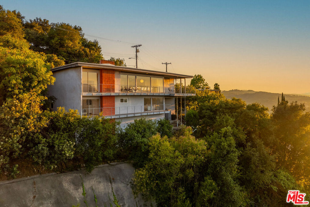"The Thomas Young House", 1962. Architect William E. Mader, AIA". LA-based comedian Thomas Young enrolled the talents of William E. Mader, AIA, to design this mid-century property atop the Hollywood Hills. Mader was an an alumnus of USC's renowned School of Architecture, and designed notable mcm properties throughout LA and Palm Springs before eventually becoming future principal architect for the Irvine Company. Located just off iconic Mulholland Drive, the "Thomas Young Residence" is one of 14 distinctive homes that form the Eureka Summit Residential Historic District. Mader positioned the 2,405 SqFt home to fully embrace its panoptic views, stretching from Universal City to Woodland Hills and framed by floor-to-ceiling windows that invite the Valley landscape - including mountains views - into daily life. With minimal street setback, and deliberate absence of traditional front and side yards, the Young residence emphasizes openness, privacy and modernism's embrace of nature and light. Historic marketing materials for Eureka Summit (a subdivision of Wrightwood Estates) pulled no punches: "If you are looking for an ordinary house in an ordinary street with ordinary dark, old-fashioned living... don't come to see." The open main level features the original stone facade fireplace, frosted Mondrian-style windows, and remodeled living and dining spaces finished in beautiful prime oak hardwood floors. The updated kitchen includes Bosch stainless appliances, while a large home office offers flexible use as a potential third bedroom. Downstairs, two bedrooms include a primary bath suite with dual sinks and walk-in shower while the secondary bath has a sunken tub with north-facing Valley views. A rear deck runs the length of the house and includes a dedicated patio space. A side-by-side washer/dryer is located in the main hallway, and an attached two-car garage provides ample storage space. Minutes from the West Hollywood and Studio City business districts, the "Thomas Young Residence " offers quick access to amenities as well as an artful blend of mid-century design and contemporary updates.