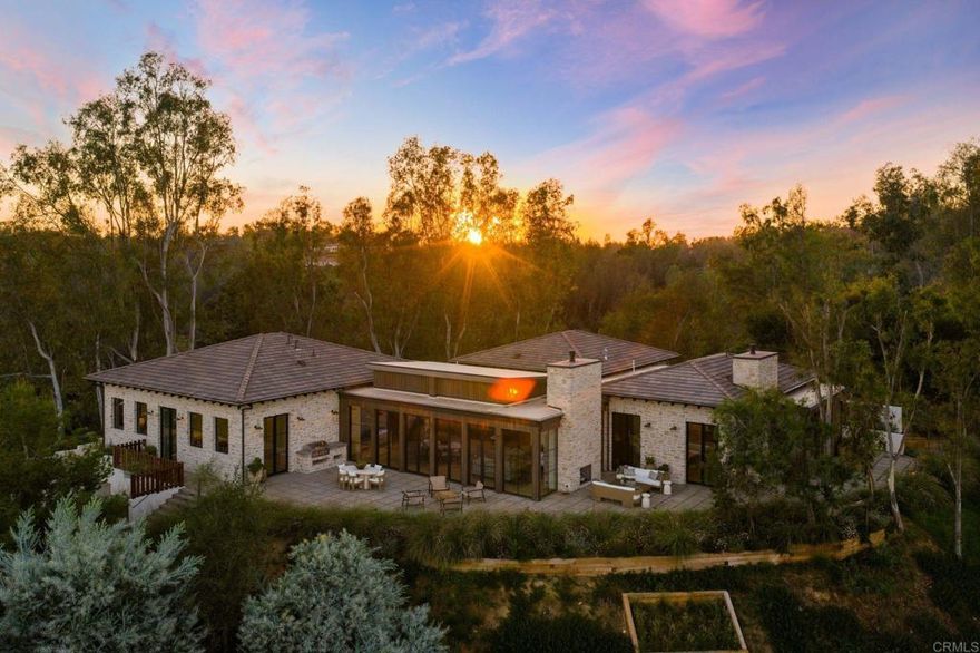 A New Construction Masterpiece Above the Clouds in the West Side Covenant of Rancho Santa Fe. Perched upon a desirable hilltop in Rancho Santa Fe, this spectacular new construction ranch estate with a modern twist was completed in 2025 and offers a top-of-the-world location, granting rare sweeping views from East to West that allow you to live in serenity among the treetops. It is a private sanctuary, a genuine West Side Covenant home, that flawlessly merges timeless craftsmanship with contemporary luxury. The 4,359 SF, single-level residence is set on 1.54 meticulously maintained acres. It delivers 4 bedrooms, 3.5 spa-inspired bathrooms, a dedicated office, and a media room, all unified by an effortless, transparent indoor-outdoor flow. The architecture masterfully blends warm natural stone, rich wood accents, and expansive walls of glass that act as art, flooding the interiors with curated light. Inside, vaulted ceilings with exposed beams soar above the open living and dining spaces. The chef’s kitchen, a study in functional elegance, pairs bespoke custom cabinetry with high-performance stone surfaces, a commanding center island, and professional-grade appliances. Thoughtful design details, including wide-plank oak flooring and meticulously curated lighting, ensure every corner of the home feels both refined and utterly comfortable. The private primary suite is a true retreat, opening directly onto the patio with restorative views across the rolling hills. Outside, the property is framed by multiple entertaining terraces and lounging areas, complete with an outdoor fireplace, the perfect settings for taking in the daily, vibrant sunsets. Beyond the main residence, amenities include an 827 SF 3-car garage and meticulously landscaped grounds designed for low-maintenance beauty. This newly built estate offers a rare combination of contemporary design, single-level ease, and an unmatched location that is just minutes from the beach, the iconic Racetrack, polo fields, world-class golf, top-rated schools, and the charming Village of Rancho Santa Fe.