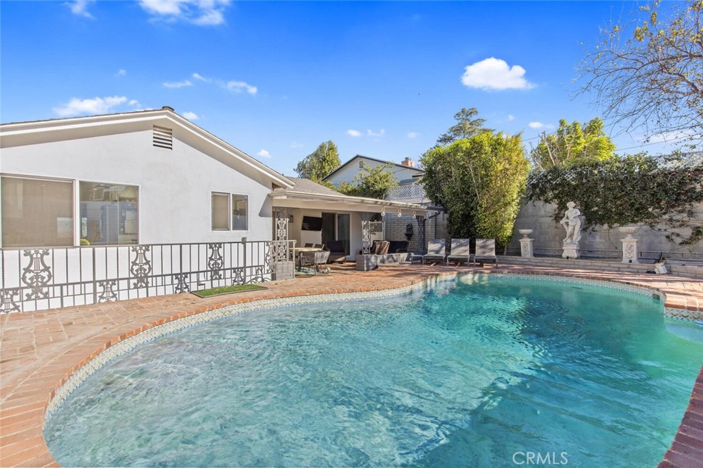Nestled south of Ventura Blvd in the highly sought-after Woodland Hills neighborhood, this beautifully remodeled residence exudes modern sophistication and comfort. The spacious living room is highlighted by a dramatic raised-hearth fireplace with a stacked-stone surround, offering a cozy focal point and expansive views of the valley below. Flowing seamlessly into the dining area, the galley kitchen is a chef's dream. Featuring sleek white cabinetry, pristine quartz countertops, and top-of-the-line stainless-steel appliances, this space is both stylish and functional. A sunlit breakfast nook offers a perfect spot for your morning coffee, soaking in natural light. The home's private retreats provide a serene escape, with the primary bedroom boasting direct access to the backyard. Two beautifully updated bathrooms showcase spa-like features, including a soaking tub, rainfall shower, and double vanity in one of the baths. Enjoy outdoor living with ease sliding glass doors open to a covered patio, ideal for al fresco dining or weekend relaxation. Take a refreshing dip in the sparkling pool, surrounded by lush landscaping, or unwind in this peaceful oasis. With its unbeatable location and impeccable design, this Woodland Hills gem is the perfect place to call home.