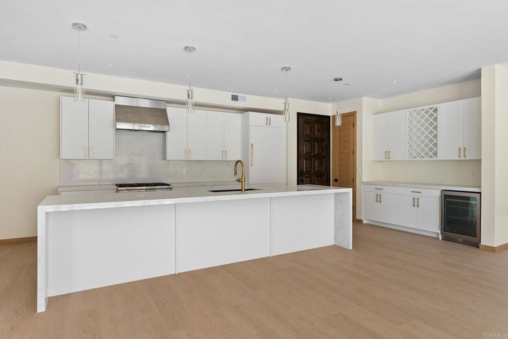 NEW CONSTRUCTION – Beautiful single-level (no stairs), first-floor unit at Roosevelt Nine Condos. Home features an open-concept true chef’s kitchen showcasing an oversized island, white custom European slab-style cabinets, Thermador appliances (fridge and dishwasher paneled to match), gold hardware, a Kohler touchless faucet, and a professional-grade Thermador hood vent. Corian Quartz counters, matching backsplash, and a dramatic waterfall island create a modern, high-end look. Dining area includes a large custom built-in seating bench with extra storage. Solid core doors from Urban Doors and matching wood baseboards run throughout, complemented by luxury motorized window treatments in bedrooms. Spacious primary suite offers a large sliding glass door opening to the private backyard and filling the room with natural light. Attached primary bathroom features designer tile, a custom glass shower enclosure, and a fully built-out walk-in closet. Located in the heart of Carlsbad Village, this home is a short stroll to countless dining options ranging from Michelin-rated restaurants like Jeune et Jolie and Lilo to casual favorites like Pure Taco and everything in between. The large, side-by-side attached garage (424 sf) will include epoxy flooring and custom storage cabinets, along with an EV outlet for car charging. Comes with owned solar. Unit is complete and power / gas are on. This an incredible opportunity to move into a highly upgraded brand-new home in one of Carlsbad’s most vibrant neighborhoods.