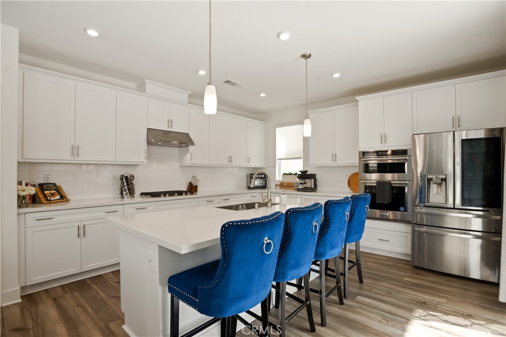 Looking for a home with an attached casita? Welcome to this beautifully upgraded residence in the sought-after Greenway community at The Preserve in Chino—where luxury, convenience, and thoughtful design come together effortlessly.This move-in-ready home features paid-off solar panels, delivering significant energy savings and peace of mind from day one. The multi-generational en suite on the main floor is ideal for extended family, guests, or as a private retreat. With its own bedroom, full bathroom, kitchenette, and cozy living area, it offers unmatched comfort and privacy. Designed for both entertaining and everyday living, the open-concept layout boasts a gourmet kitchen with quartz countertops, a walk-in pantry, and an upgraded appliance package. A spacious center island easily accommodates four barstools—perfect for casual dining and social gatherings. The adjoining living and dining spaces are highlighted by luxury vinyl flooring, adding both style and durability. Upstairs, the primary suite offers a tranquil escape with a large walk-in closet and spa-like bathroom featuring dual sinks, a soaking tub, and separate shower. You'll also find four additional bedrooms—including one with its own bathroom. A versatile office/fitness room and a convenient upstairs laundry room complete the second level. Additional highlights include plantation shutters throughout, custom backyard hardscape and landscaping, and a 3-car tandem garage equipped with an EV charger. As a resident of The Preserve, you'll enjoy access to three exclusive clubhouses with fitness centers, pools, spas, sports courts, and more. Discovery Park, located next door, features a dog park, Tai Chi garden, basketball court, and obstacle course. Zoned for highly-rated Chino and Chino Hills schools and just minutes from shopping, dining, and entertainment at The Town Center at The Preserve, this home offers an unmatched lifestyle in one of Chino's most desirable communities. Don’t miss your chance to own this upgraded gem.