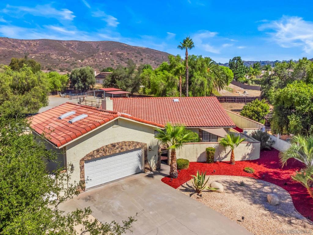 This home has it all! Single level ranch home featuring 4 car garage, pebble-tech pool and spa, and spacious backyard in the heart of the SDCE! Tucked into the end of a quiet cul-de-sac with a view of Simon County Preserve, this home features 3 bedrooms and 3 baths and a large open floor plan perfect for entertaining. This home is extremely private with block walls creating a front courtyard and private backyard. Pebble-tech pool features both propane and solar heaters and adjacent aluminum patio cover. Property has been cross fenced for horses with a large barn cover and corrals. Easement road behind the property allows for delivery and trailer access. Ride out of the property to local riding trails. Inside the home is a spacious kitchen featuring granite counters and stainless steel appliances. The large adjacent dining room has a wainscot finish and lots of windows! Living room has a fireplace and media niches. Two of the three bedrooms have en suite bathrooms including the primary which has recently been updated. All rooms have large closets with ample storage and extra built in shelves. Walking distance to Barnett Elementary and 10 minutes to downtown Ramona. Experience all the Country Estates has to offer including the clubhouse with a restaurant, sports bar, event space, boutique hotel, 18 hole golf course, tennis and pickleball courts, and a community pool and spa. The community also provides a vast trail system for horse riding, biking, or hiking, and a 5-acre community park with a second pool, bandstand, and grassy areas for picnics and community events.
