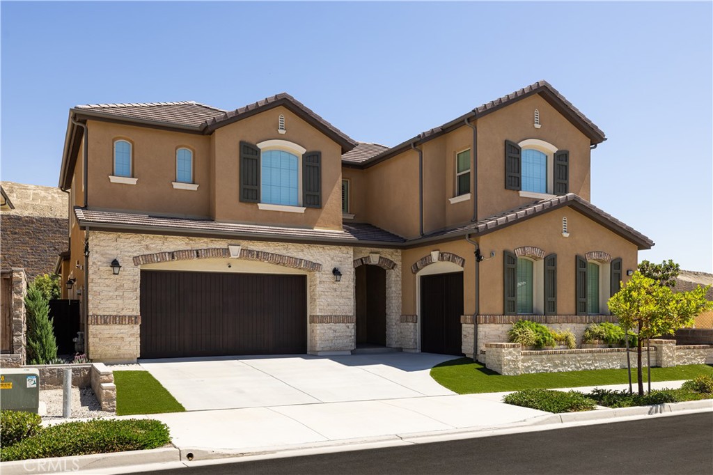 Newly built in 2022 within the coveted gated community of The Oaks at Portola Hills, this residence blends fresh contemporary design with everyday comfort.
Under soaring ceilings, the great room opens through pocket sliding doors to the private backyard, creating a seamless indoor-outdoor connection. The kitchen features quartz countertops, a stone and porcelain mosaic backsplash, soft-close cabinets, a large eat-in island, and a walk-in pantry plumbed for a beverage cooler. Commercial-grade KitchenAid appliances include a six-burner gas cooktop with built-in electric grill and two full built-in ovens—all complemented by a fireplace-warmed dining area with a custom built-in lighted china cabinet, complete with remote and granite top. Flanking the fireplace, additional built-in displays with granite tops add style and function.
Smart features include a motorized kitchen shade (remote- and app-controlled), a solar screen at the California room, and three Enviroblind security shields at the kitchen, California room, and downstairs primary slider—each with remote and hand-crank operation. Waterproof rigid core luxury vinyl oak plank flooring on the main level and primary bath, plantation shutters, and quartz finishes elevate the interiors.
The main-level primary suite opens directly to the backyard and offers a spa-like bath with limestone slab-topped dual sinks, a walk-in shower, and a freestanding soaking tub. Upstairs, an en suite bedroom serves as a second primary, while a loft/media room provides space for entertaining or a home office. Two secondary bedrooms, currently used as offices, feature updated baths with quartz finishes and glass closures.
The backyard combines stone and turf for an inviting, low-maintenance retreat. Additional highlights include seller-owned solar, Honeywell-controlled thermostats and garage doors, EV charging, instant hot water call buttons, and two garages: a two-car garage finished with marble-style epoxy flooring, plus a separate one-car garage ideal for parking or storage.
Residents of The Oaks enjoy resort-style amenities, including a pool, clubhouse, BBQ area, dog parks, sports courts, and over 1.5 miles of hiking trails with sweeping views of Lake Forest and Trabuco Canyon. Convenient access to the 241 Toll Road and proximity to Irvine Spectrum complete this exceptional offering.