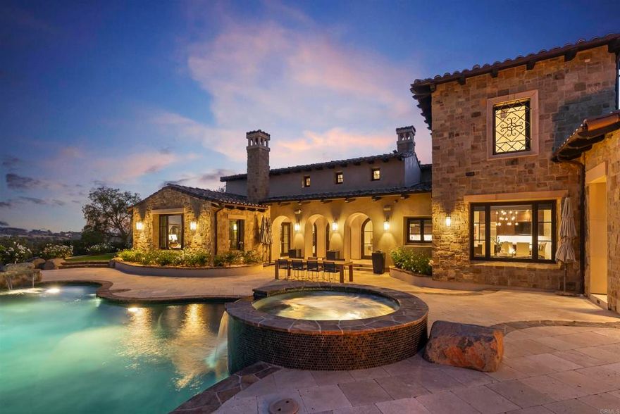 Set within the gates of Santaluz—one of San Diego's most coveted guard-gated country club communities—this 7,311 sq. ft. estate offers a rare blend of architectural elegance, thoughtful upgrades, and resort-inspired living. Positioned along the 13th green, with expansive golf course views, the residence captures a serene sense of privacy while embracing the natural beauty of its surroundings.  Designed by Steve Murcko & Associates, the European-inspired estate reflects luxurious architectural attention to detail, from soaring vaulted ceilings to striking groin vault accents, complemented by arched doorways, custom built-ins, and designer stone finishes that create both intrigue and a welcoming atmosphere . Interiors unfold with a seamless flow, equally suited for intimate gatherings and large-scale entertaining, with multiple fireplaces, a wine cellar, a billiards room with wet bar, state-of-the-art theatre and a Savant whole-home entertainment system setting the stage for everyday living and celebration alike.  At the heart of the home, the recently remodeled kitchen combines custom cabinetry with Taj Mahal quartzite countertops and professional-grade appliances, anchored by an oversized island, butler’s pantry, and sunlit breakfast nook. 5+ bedrooms and 5 full/2 half baths, including a primary suite with marble finishes, heated floors, dual closets, and a fireplace, provide comfort and retreat for family and guests.  Expansive patios open to a private backyard oasis with a saltwater pool and spa, outdoor fireplace, barbecue kitchen, and fruit tree grove, all framed by lush landscaping and golf course views. Thoughtful upgrades such as a fully owned 23kW solar array and whole-home reverse osmosis system reflect a commitment to both luxury and sustainability.  7795 Sendero Angelica is more than a residence—it is a sanctuary, a gathering place, and a legacy estate within one of San Diego’s most celebrated guard-gated country club communities.