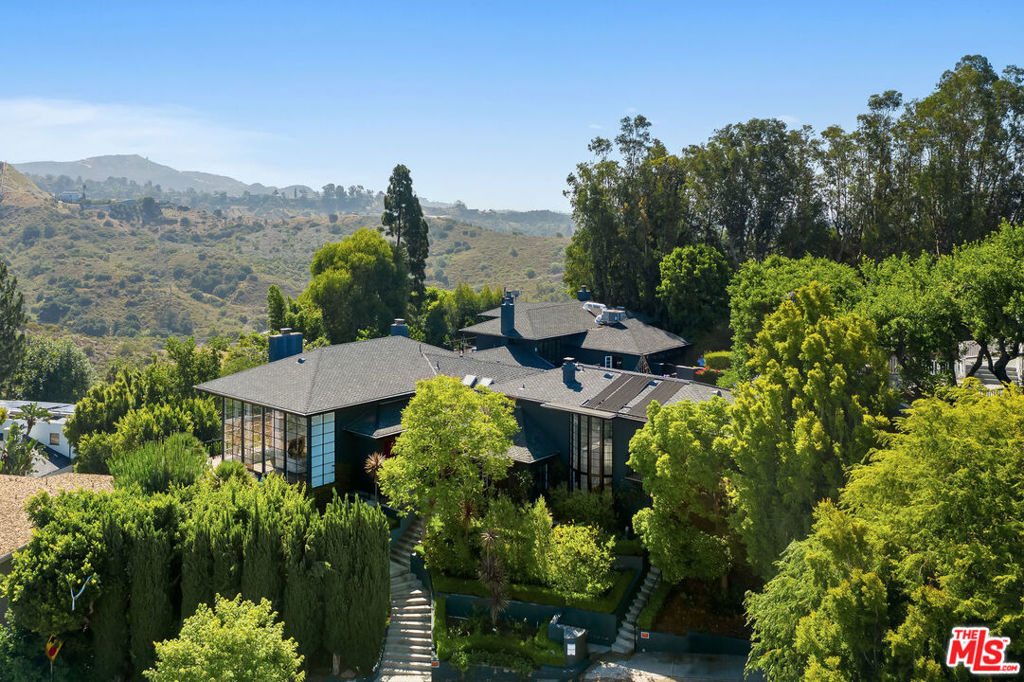 World class East Hollywood compound with spectacular views, privacy and elevated style. Unparalleled scale and warmth throughout with soaring ceilings and walls of glass framing the city views. With over 6,000sf of architectural flourishes the home encompasses 4 bedrooms, 6 bathrooms, a great room, dining room, living room, office, bonus room and an attached 2 story guest house with a recording studio. The kitchen equipped with top of the line appliances, a large island and dining table opens seamlessly to the pool that is surrounded by an abundance of lounge space. The expansive deck is accessible from each living area and provides ample entertainment space. 2 story grand master suite complete with an elite bathroom, walk in closet and spacious sitting area opening directly to the pool. This listing consists of 2APN's: 5577-001-013 and 5577-001-008.