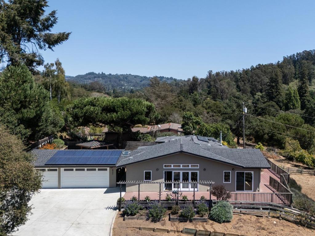 Bathed in natural light and framed by mountain vistas, this single-level 2,405 sq. ft. residence offers spacious living, flexibility, and coastal convenience. Designed with four bedrooms, three full baths, an office, and inside laundry, the home balances comfort and function. A seamless attached addition flows with the main house and works beautifully as a TV lounge, playroom, game room, or deluxe primary suite. It can also be closed off as a complete in-law unit or rental with private entrance, kitchen, living room, bedroom with walk-in closet, full bath, and private deck. At the heart of the home, a private courtyard with gazebo and built-in seating opens to wraparound decking for indoor-outdoor living. The 14,593 sq. ft. lot features mature landscaping, a prolific citrus tree, and flat space below the home, ideal for a garden, orchard, or sport court. Additional highlights include a detached three-car garage with breezeway, leased solar, in-garage EV charger, wood burning stove, hardwood floors, skylights, floor-to-ceiling windows, and solid core natural wood doors. Minutes to Aptos High, Aptos Village, local beaches, Watsonville Airport, and convenient commute routes.
