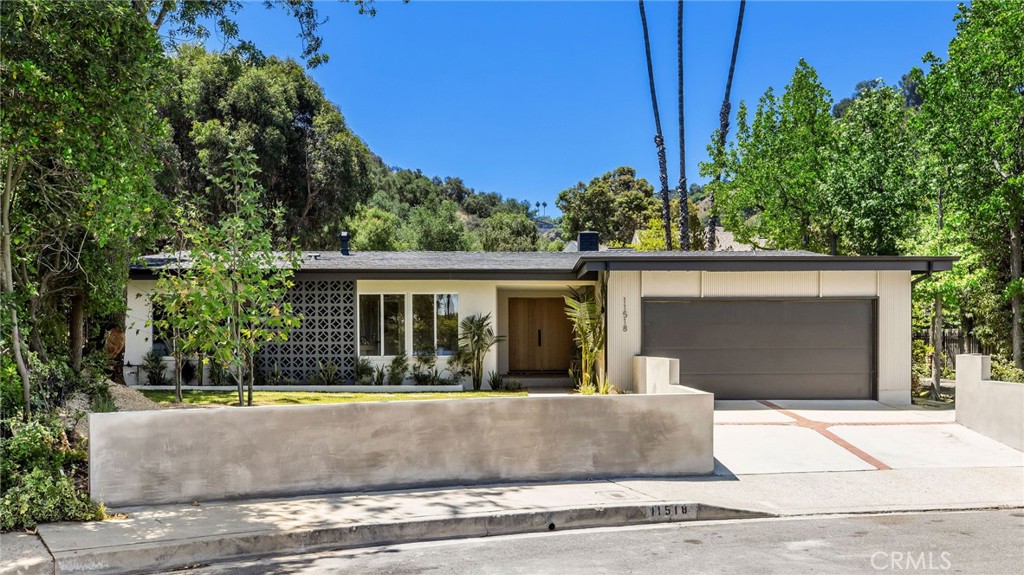 Nestled in the hills above Fryman Canyon, this 3BD/3BA Mid-Century home in Studio City is a timeless architectural gem. Originally designed by David Freedman AIA, the residence has been thoughtfully reimagined with elegant finishes, an airy open layout, and effortless indoor-outdoor flow. Upon entry, you're welcomed into an expansive living room featuring fluted accent walls, a sleek fireplace, and a striking atrium that infuses the space with natural light. The living area connects to the formal dining room, where sliding glass doors in both spaces open to the expansive backyard, perfect for entertaining. Built for a chef, the gourmet kitchen is appointed with high-end Thermador appliances, sparkling countertops, bar seating, and abundant cabinetry. The primary suite serves as a tranquil retreat, complete with a walk-in closet, additional built-ins, and direct access to the backyard. The en-suite bath features dual floating vanities and a luxurious walk-in shower with a custom, built-in bench. Two additional bedrooms, one with an en-suite bath are ideally situated near the primary, each filled with natural light and offering ample storage. Outside, enjoy a lush grass lawn, hillside vistas, and a built-in barbecue, ideal for dining al fresco. Located moments from Fryman Canyon's scenic trails and the highly acclaimed Carpenter Community Charter School, this home offers the perfect balance of comfort, elevated living, and utmost convenience.