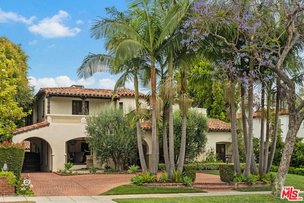 A Stunning updated Spanish on one of the most desirable streets in coveted Beverly Hills flats still boasts the original hand carved doors and stained- glass windows. Each room of the house has a special charm from the sweeping staircase with original deco tile risers to the bright and airy dining room to the dramatic fireplace and stained-glass wall in the living room. The large and spacious family room has impressive French doors that open onto an enormous, covered patio with BBQ and wood burning Mugnaini pizza oven. The expansive chef's kitchen is adorned with Calcutta Borgia porcelain counters, and boasts double Wolf ovens, multiple Fridges, dishwashers and wine fridges. One of the four spacious bedrooms upstairs is being used as a movie room replete with surround sound and built-in refrigerators, so sodas, candies and ice-cream are only an arms-reach away. The maid's room is currently being used as an office. The primary suite has a view of hills and treetops and overlooks a very private backyard with swimming pool and fireplace. The garage has been converted into two rooms, a pool room with fridge, steam shower and a separate gym. The porte cochere and driveway allows parking for six cars. The house has a security system and cameras. Finally, automated systems create a smart home operated by both touch screens and phone app.