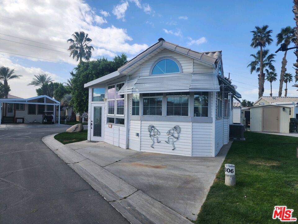 This upgraded '94 Hallmark is beautifully upgraded with ceramic, designed tile throughout, that carries the same design to the electric shutter, enclosed patio. The warm blues throughout, brings a very relaxing surrounding to sit and relax in your home away from home. The PM sets on a corner lot, offering a large side yard, as well as a concreate drive area, large enough for 2 vehicles, which is an wonderful amenity for any unit in this community. The insulated, finished off shed, houses the washer and dryer and also offers a closet for extra storage. This all located in a 55+ community that has a 3 par golf course, chipping green, putting green, 9 hole mini golf, pickleball and tennis courts, bocce ball, an indoor shuffleboard courts, 2 clubhouses with pools and jacuzzies and an additional 4 satellites with pool, jacuzzies and mail boxes. This is all within a 24 hour gate guarded community of 801 lots, that consist of a combination of Park Models and RV lots, where you own the land. The resort has a limit of 270 day occupancy. It is a perfect place to spend your holidays in the sunshine.