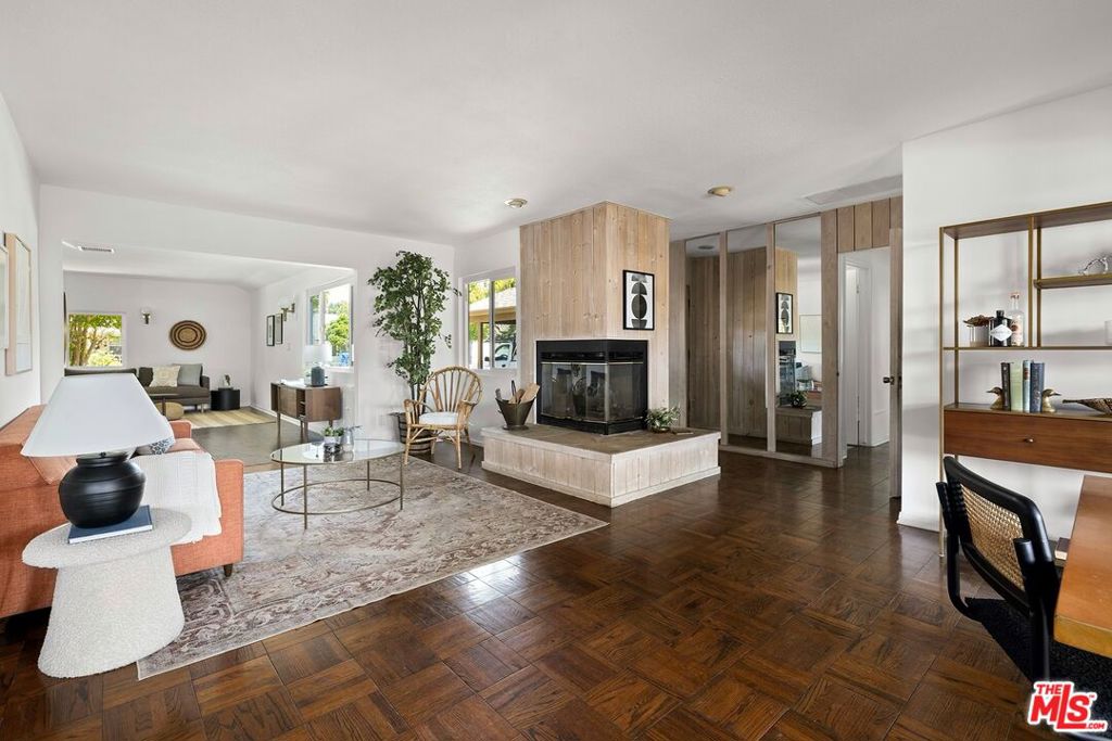Tucked away on a peaceful street in Northridge, this sunny mid-century home blends warmth, charm, and thoughtful updates. Step inside and find a bright and open living and dining area. There are real hardwood floors throughout and a cozy fireplace anchors the living area. A wall of windows flood the space with light and creates a seamless connection between indoor comfort and the outdoors. Just off the main living area, there is a spacious den with its own half bath - offering flexibility as a home office, studio, or playroom. The updated kitchen features quartz countertops, new cabinetry, and stainless steel appliances. Set apart from the main living area for added privacy, there are three well-sized bedrooms. All light and airy and feature hardwood flooring and green views of the yard and landscape. There is a shared full bathroom, complete with tub and a separate shower. The backyard feels like a private escape, with a lush lawn for relaxing or play, plus plenty of patio space for dining and entertaining under the California sun.