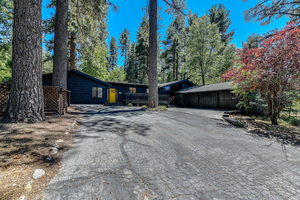 Mid-century modern design blends with mountain ranch living in this beautifully updated sanctuary just minutes from town and the Idyllwild Arts School. Set on a .41-acre lot, this home offers architectural charm, natural beauty, and modern comfort. Inside, soaring beamed ceilings and abundant natural light create a warm, open atmosphere. With five bedrooms, four bathrooms, and an attached casita, the flexible layout suits a variety of living needs. Two grand river rock fireplaces and a potbelly stove in the primary bedroom add cozy mountain character. The kitchen features terrazzo countertops, green Zia tiles, dual Ravioi brass sinks, and striking mid-century modern lighting. Saltillo tile floors run through the main living areas, while a new Ecobee system offers central heat and whole-home music streaming. Outside, enjoy rose gardens, mature fruit trees, a jacuzzi, and a large outdoor dining area. Extras include a three-car garage, new water heater, and rare sewer connection.
