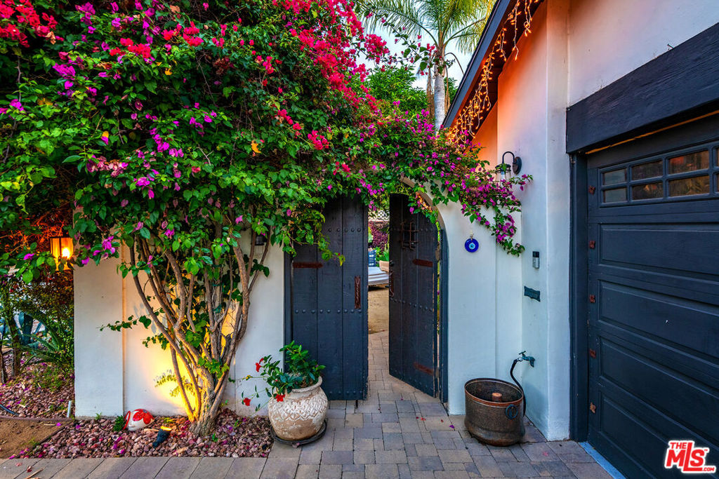 Designer-Curated Spanish Sanctuary!! Step into this beautifully remodeled Spanish-style sanctuary in coveted West Toluca Lake and immediately feel the harmony of old-world elegance and modern luxury.Behind a private floral wall, two wooden doors open to a tranquil front courtyard, setting the tone for this meticulously updated 3-bedroom, 2-bathroom home. Inside, an open floor plan unfolds beneath soaring vaulted ceilings, complemented by exposed beams and arched windows that bathe the space in natural light. Designer wall coverings, Moroccan chandeliers, and a striking black-and-white palette unify the interiors, while custom built-ins add both functionality and flair.The formal living room features a charming bay window, creating a cozy nook, and a built-in desk adjacent to a statement-making tile-surround fireplace. A floor-to-ceiling glass wine cabinet elegantly separates the living and family rooms, enhancing the home's sophisticated flow.The gourmet kitchen is a chef's dream, fully renovated with thick quartz countertops, a breakfast bar, and top-tier stainless steel appliances including Thermador 6 burner with griddle and 2 ovens. A Control4 surround sound system integrates seamlessly throughout the home for effortless ambiance and entertainment. French doors and sliders open to two oversized stone patios, seamlessly extending the living space outdoors.The private backyard is a serene escape, complete calming fountains (5 total on the property), mature greenery, citrus trees in Mediterranean pots, and a lush lawn. A built-in BBQ with bar and a covered lounge area create the perfect setting for alfresco dining and entertaining.The primary suite offers three spacious closets including a in and a luxurious ensuite bath. Two additional bedrooms and a beautifully updated bath continue the home's story of refined design and comfort. Additional highlights include a whole-home water softening system and alkaline water dispenser, an oversized two-car garage, professionally designed landscaping, 5 year old roof and copper plumbing. Set back from the street and enveloped by verdant surroundings, this home offers both privacy and curb appeal blending timeless Spanish architecture with elevated modern living in one of West Toluca Lake's most sought-after locations.