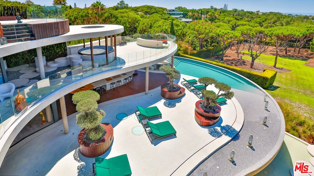 "The Ballerina Villa", Portugal's most outstanding and collectable residence offered for sale. The "Newport Beach" of Portugal! An exquisite testament to luxury living nestled within an esteemed enclave of Central Algarve, Portugal, this 6 Bedroom, 8 Bathroom, ~12,000 SF (16,000+ SF including terraces), on a 30,000+ SF lot unparalleled residence, evoking the visionary designs of architect John Lautner, seamlessly merges contemporary sophistication with timeless elegance, setting an unprecedented standard for opulent living in Portugal. As you enter through the grand double-height entrance, adorned with verdant greenery cascading down a soaring circular floating staircase, you are immediately enveloped in an ambiance of tranquility and refinement. The villa's unique curved modern architectural design offers panoramic ocean views, beckoning you to indulge in the epitome of coastal luxury. Designed for extravagant entertaining, The Ballerina Villa boasts a rooftop deck and sky bar, ideal for hosting grand soires beneath the stars. Expansive covered terraces and sprawling lawns provide ample space for outdoor leisure, while the cascading infinity pool, bordered by underwater walls of glass, seamlessly merges the pool into the indoor spaces, creating an enchanting atmosphere. Inside, the towering circular floating staircase commands attention, leading to a realm of luxurious amenities. Lush interior green walls blur the boundaries between indoors & outdoors, while the spa-inspired primary bathroom rivals that of the world's most exclusive resorts, offering a sanctuary of relaxation and indulgence. Entertain in style within the lavish game room and entertainer's lounge, or savor gourmet meals in the dining room, complete with a 20-person table. For those seeking wellness and rejuvenation, a state-of-the-art home gym and spa await, featuring an interior cold pool and hot saunas. From meticulously landscaped gardens to extraordinary attention to detail, The Ballerina Villa epitomizes sophistication and refinement, offering a lifestyle of unparalleled luxury and exclusivity. Experience the pinnacle of coastal living at The Ballerina Villa where every moment is imbued with unparalleled elegance and distinction.