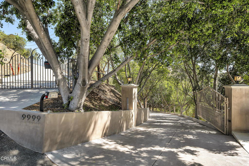 Tucked at the end of a tree-lined private drive, 9999 Wornom Ave offers a rare blend of tranquility, architectural charm, and indoor-outdoor living--just minutes from the city. From the moment you pass through the remote-controlled gate and wind down the landscaped driveway, it's clear this is no ordinary property. Surrounded by mature trees and elevated terrain, this gated estate delivers a remarkable sense of peace and privacy.A formal double-door entry opens to an airy layout with immediate views of the living room, dining area, and a one-of-a-kind British-style pub bar--complete with a granite countertop and classic charm. The home flows easily from one gathering space to the next, offering elegant tile flooring, generous ceilings, and abundant natural light throughout.The family room features a raised-hearth fireplace, high ceilings, and French doors that open to the front yard patio. It's a versatile space--ideal for quiet evenings or casual entertaining. Just beyond, the kitchen impresses with granite countertops, a large center island with Thermador cooktop, stainless steel appliances, and a bay window over the sink that looks onto greenery. A built-in desk with upper cabinetry makes this space both beautiful and functional.The dining room accommodates 6-8 guests with ease and opens to the backyard for seamless indoor-outdoor entertaining. One of the home's most unique features is the spa room--complete with skylight, built-in seating, and access to the sparkling pool.The outdoor entertainment area is a showstopper, boasting a hexagonal covered patio, built-in BBQ, fridge, fireplace, and plenty of prep space. Whether you're hosting or unwinding, it's an ideal setup for Southern California living.The primary suite is located in its own wing, with dual access to the pool and front patio, custom wardrobes, and hardwood floors. A nearby second bedroom--perfect for an office, guest room, or nursery--shares access to this serene section of the home. Two additional bedrooms are located in the south wing, one with an ensuite bath and outdoor access, and the other near a full marble-finished bath and laundry area.9999 Wornom is more than a home--it's a private hillside retreat designed for comfort, flexibility, and lasting memories.