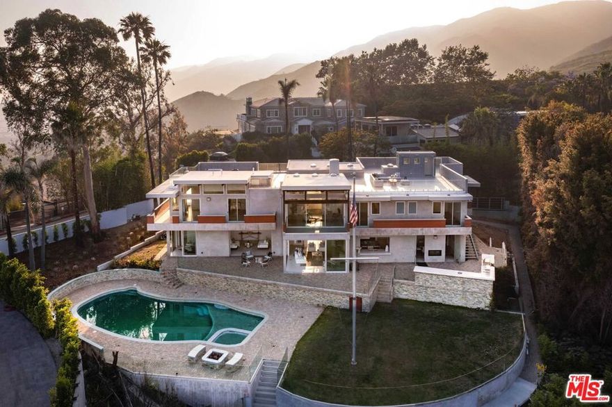 Perched behind gates with sweeping ocean and city views from the entire Santa Monica Bay to Downtown, this striking architectural estate - designed by acclaimed architect Anthony Zubick, AIA - offers the ultimate in California luxury living. Walls of Fleetwood pocket doors vanish to reveal panoramic ocean and city vistas from nearly every room, blurring the line between indoors and out. The open layout was crafted for a balance of both everyday comfort and entertaining, with a chef's kitchen outfitted with top-tier Wolf and Miele appliances that flows into expansive living and dining areas. A sculptural floating staircase leads to the upper level, home to four secondary bedrooms and a stunning primary suite with dual walk-in closets, a spa-like bath, and a wraparound terrace made for taking in the dramatic scenery. The flat backyard is equally impressive, featuring a pool, spa, outdoor kitchen, fire pit, and lush landscaping - ideal for hosting gatherings large or small. Additional features include a three-car garage and a rooftop observation deck with jaw-dropping 360-degree views. A rare opportunity that embodies elevated design, privacy, and the best of coastal L.A. living. Also available for lease.