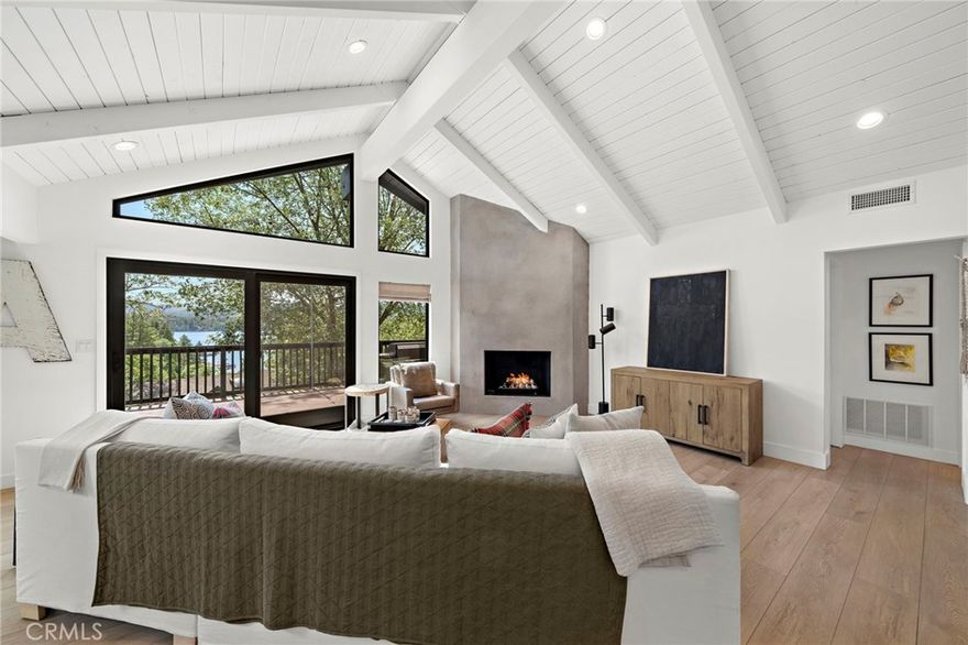 This stunning 4-bedroom, 3.5-bath mountain retreat combines modern upgrades with timeless lodge-style charm, offering captivating lake views from nearly every window. Thoughtfully remodeled in 2020-2021, the home features a bright open floor plan perfect for both comfort and entertaining. The main level showcases a dramatic great room with vaulted ceilings, expansive windows, recessed lighting, and a cozy gas fireplace that opens to a large entertainer’s deck. The remodeled kitchen is a chef’s dream with stainless steel appliances including a refrigerator, shaker-style cabinetry, pantry with pullout shelves, granite counters, peninsula with seating, and large windows framing the view. Two primary suites with spa-inspired baths—one on the main level and another on the lower level—provide privacy and flexibility, while two additional bedrooms and a spacious family room with a second fireplace and walk-out access to the lower deck with a swinging bench create the perfect retreat for family and guests. Outdoor living shines with two expansive decks crafted in durable Trek decking, ideal for gatherings, dining, or simply enjoying the mountain air and lake views. Additional highlights include dual HVAC and A/C systems with split thermostats, vinyl flooring throughout, inside laundry with washer and dryer, a finished pull-through two-car garage with automatic doors on both sides, and ample guest parking. Sold mostly furnished for a true move-in ready experience, this home is ideally located just above the trails of North Bay Cove with lake rights, peaceful morning walks, sunset strolls, and easy access off Bay Road with level parking. Just minutes from Blue Jay and Lake Arrowhead Village shops and dining, this exceptional property offers the perfect blend of modern amenities, mountain appeal, and lake lifestyle—whether as a primary residence, weekend escape.