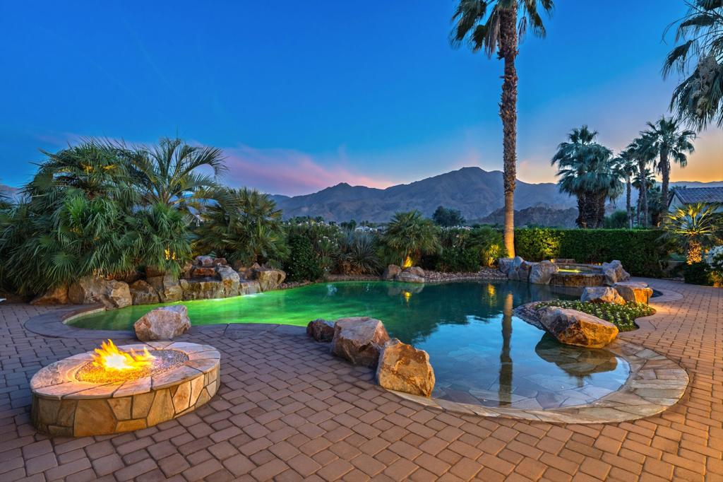 Experience refined desert living in this exquisitely appointed South-facing home, ideally located in the prestigious Andalusia Country Club. Perfectly positioned to capture unobstructed views of the Santa Rosa and Coral Mountains and the lush fairways of the Rees Jones-designed golf course, this residence offers a perfect harmony of refined style, relaxed living, and scenic beauty. From the moment you step through the private entry, you're welcomed into a thoughtfully designed interior, beautifully curated with designer furnishings and exquisite lighting that elevate every space. The open-concept layout flows effortlessly from the elegant great room to the chef's kitchen, complete with premium appliances and an oversized island ideal for entertaining. Stone flooring enhances the home's luxury, while walls of glass in the great room invite in abundant natural light and frame captivating views. The spacious primary suite is a private retreat, featuring a spa-like bathroom with dual vanities and generous walk-in closets. A detached two-room casita offers guests the ultimate comfort with its own fireplace, kitchenette, and private entrance. Step outside to discover a resort-style backyard designed for year-round enjoyment. A stunning saltwater pool with a spa takes center stage, surrounded by a covered loggia, built-in BBQ island, and inviting fire pit - perfect for sunset gatherings or stargazing under the desert skies. Come live the life you've always imagined!